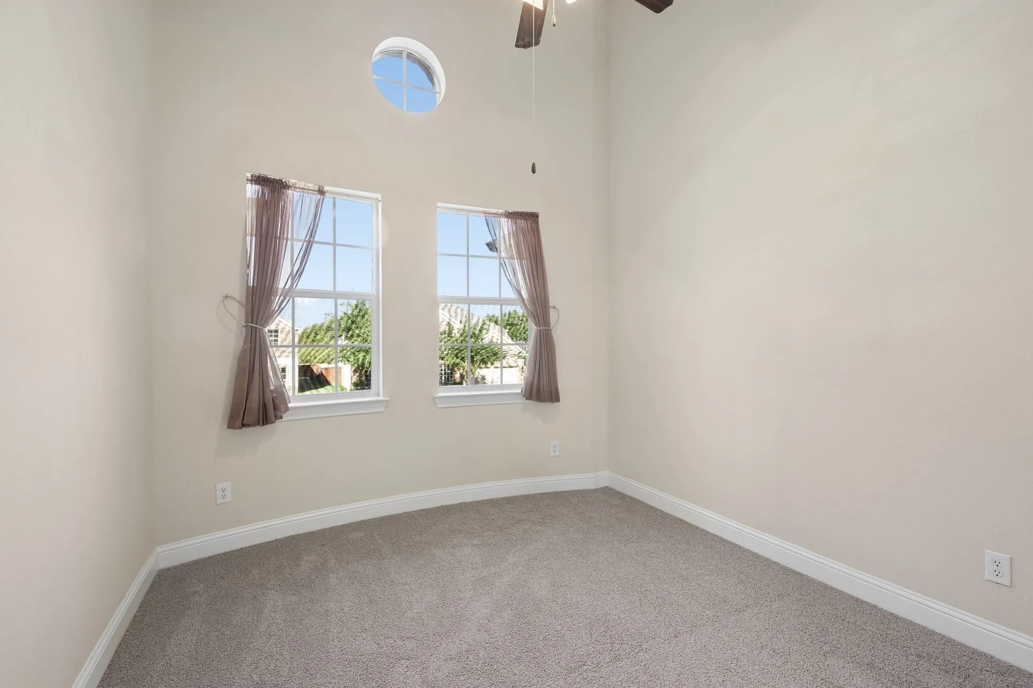 Bedroom 3 with an integrated ceiling fan, light-colored walls, carpeted flooring, and two paneled windows with an additional round window