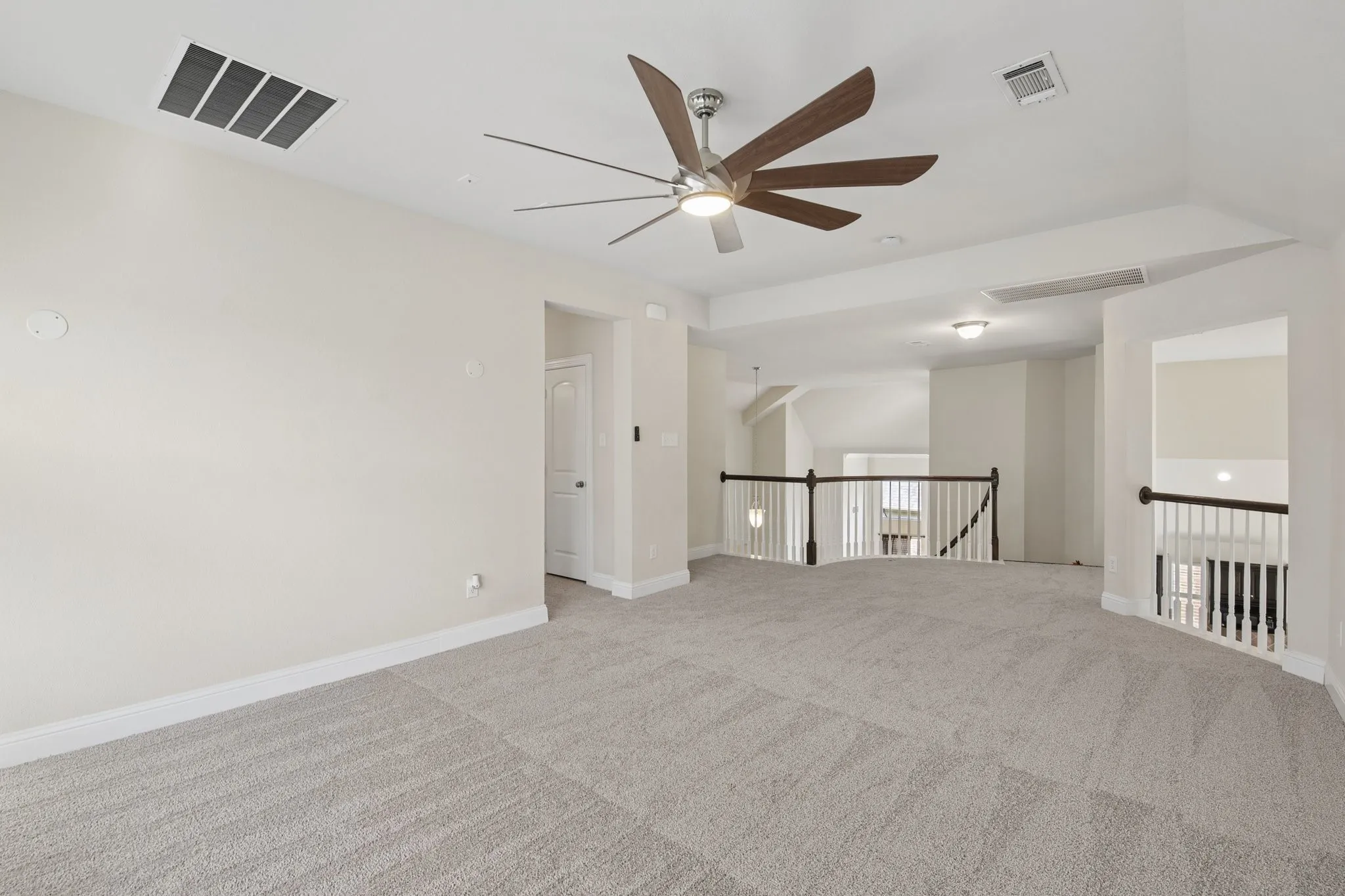 Open loft area featuring neutral carpeting, a ceiling fan with wood-finish blades, recessed lighting, and white baluster railing