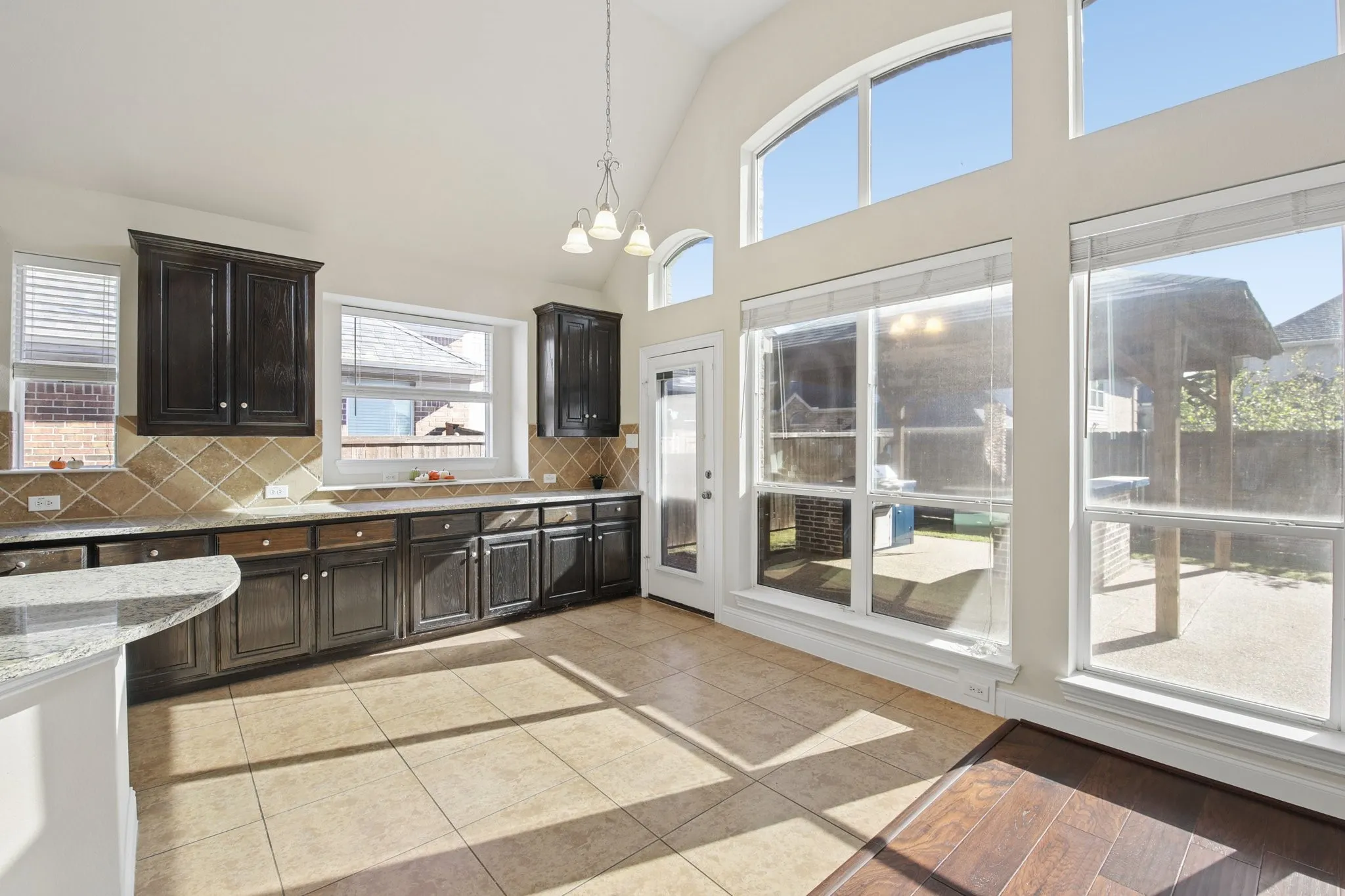 Kitchen featuring dark wood cabinetry, granite countertops, and a tiled backsplash