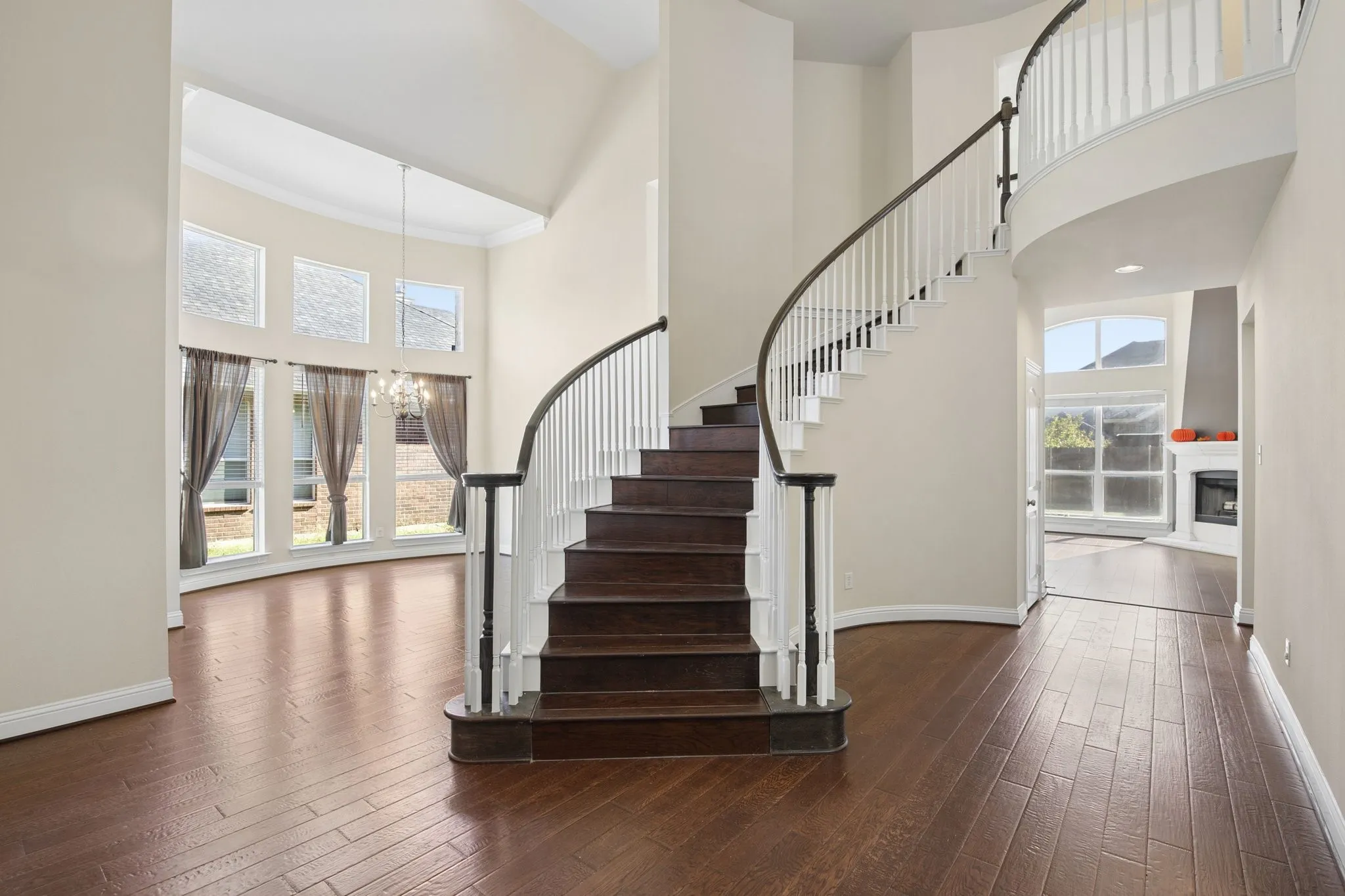Grand entryway featuring a curved staircase with dark wood treads and white risers, wood-finish flooring, and a two-story ceiling