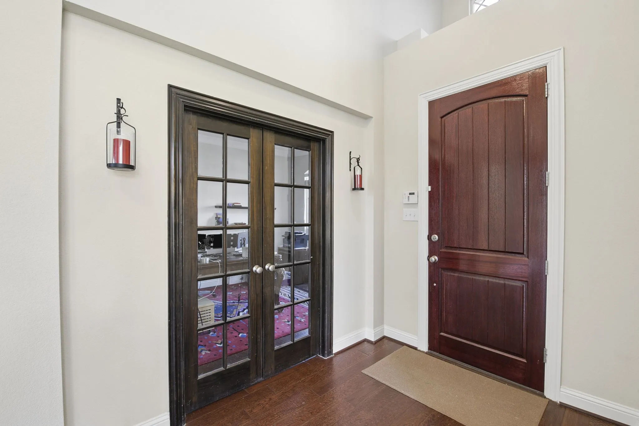Warm wood-finish flooring complements the substantial wooden entry door