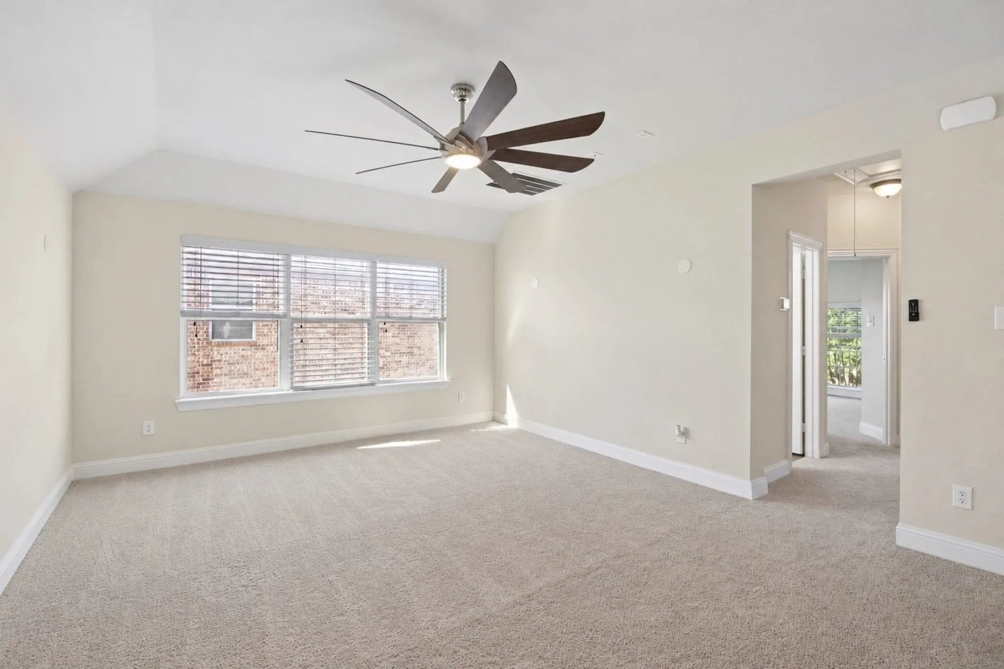 Vaulted family room ceiling with a contemporary ceiling fan, broad window with horizontal blinds, and neutral carpeting