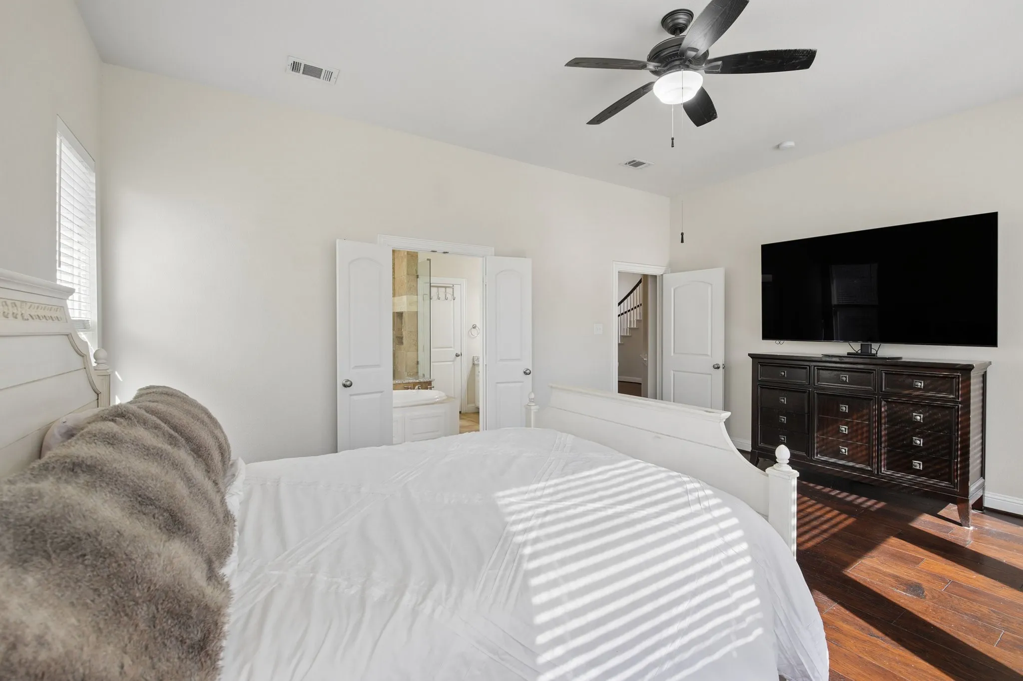 Hardwood-finish flooring, high ceilings, ceiling fan with integrated lighting, and white paneled doors