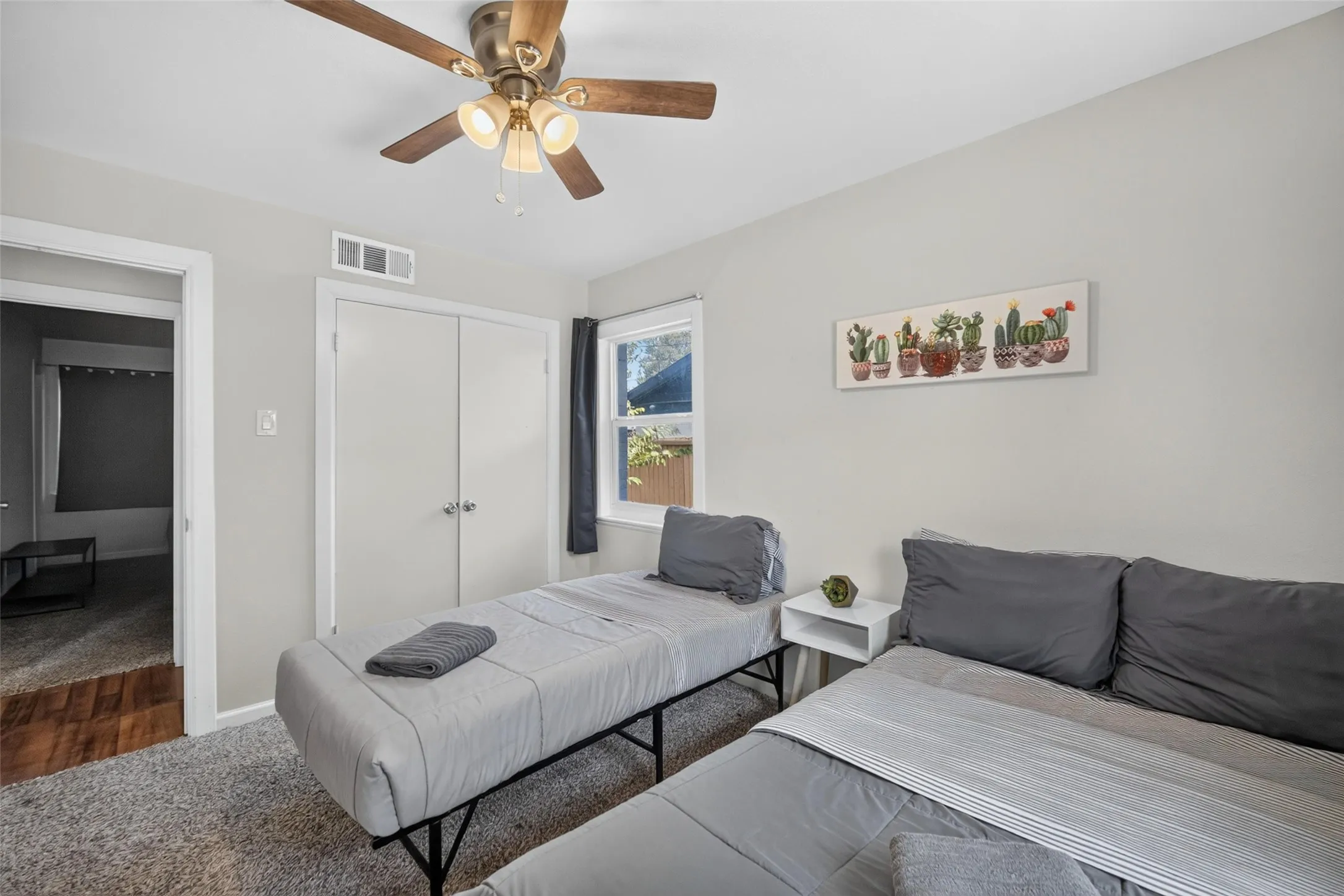 Carpeted flooring, ceiling fan with integrated lighting, window with dark-toned curtain, white bi-fold closet doors, and light-toned wall paint