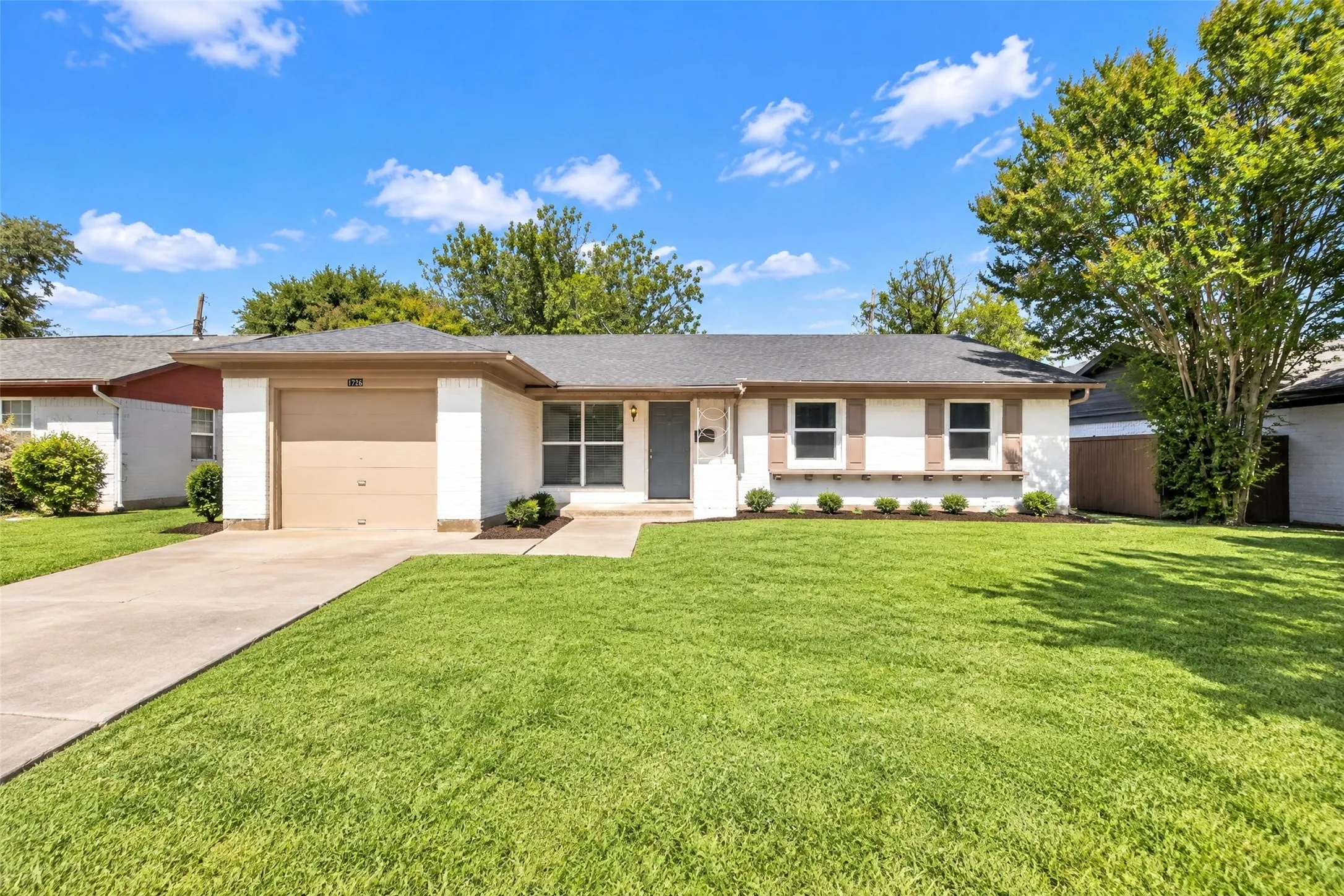 Single-story residence featuring a two-car garage, concrete driveway, and a front yard with established landscaping
