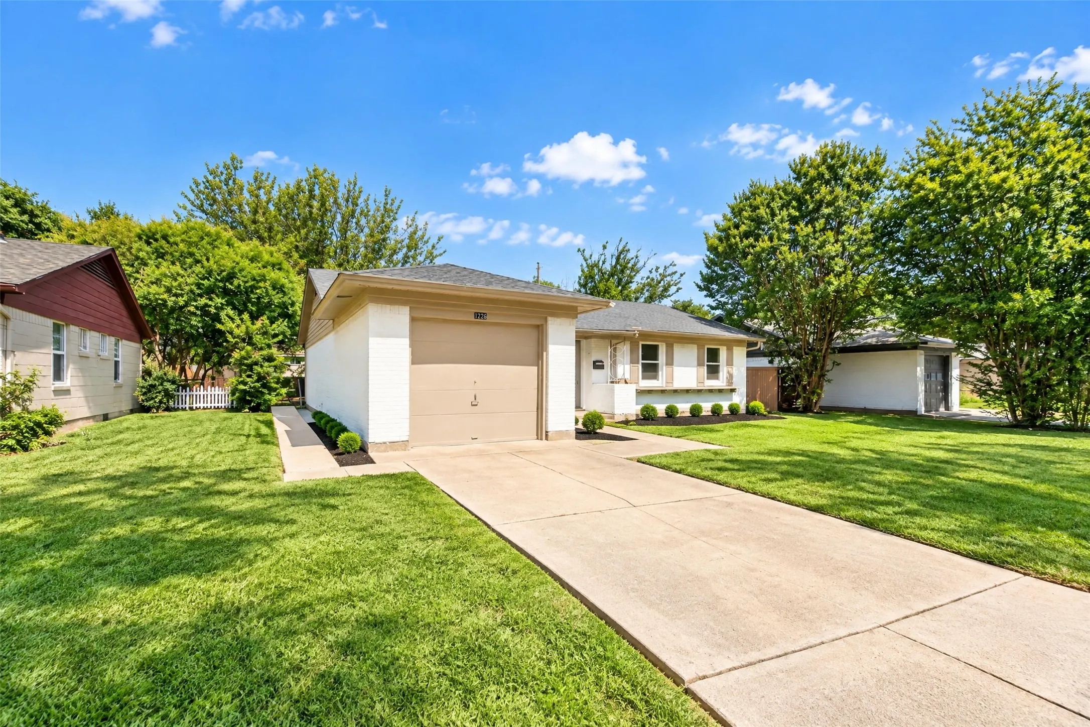 Single-story residence featuring a two-car garage, concrete driveway, and mature landscaping