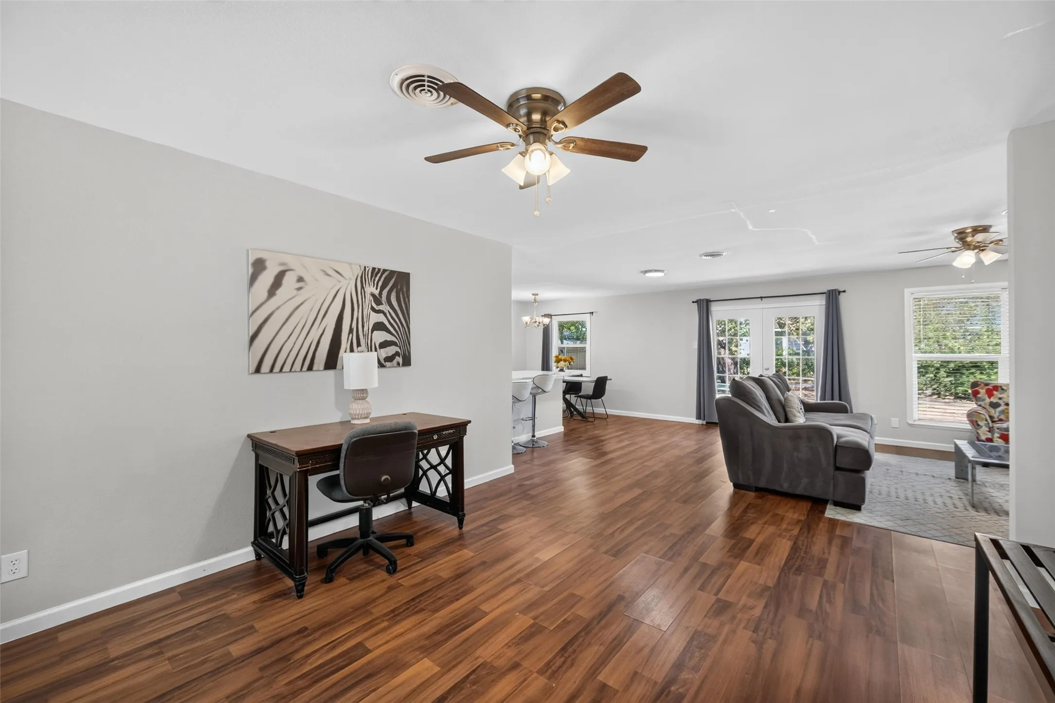 Wood-finish flooring throughout, light-colored walls, ceiling fans, and French doors