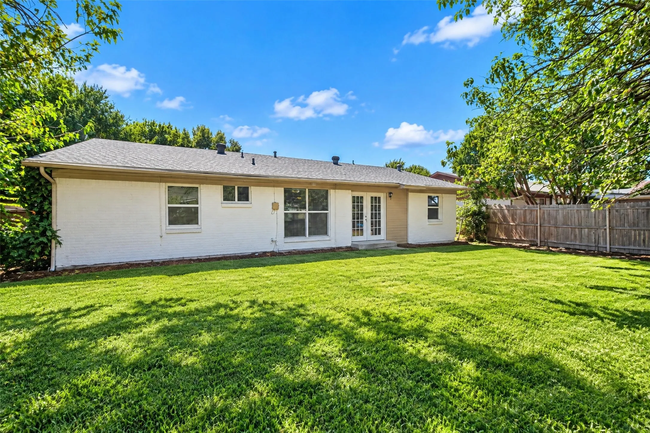 Expansive green lawn with a privacy fence