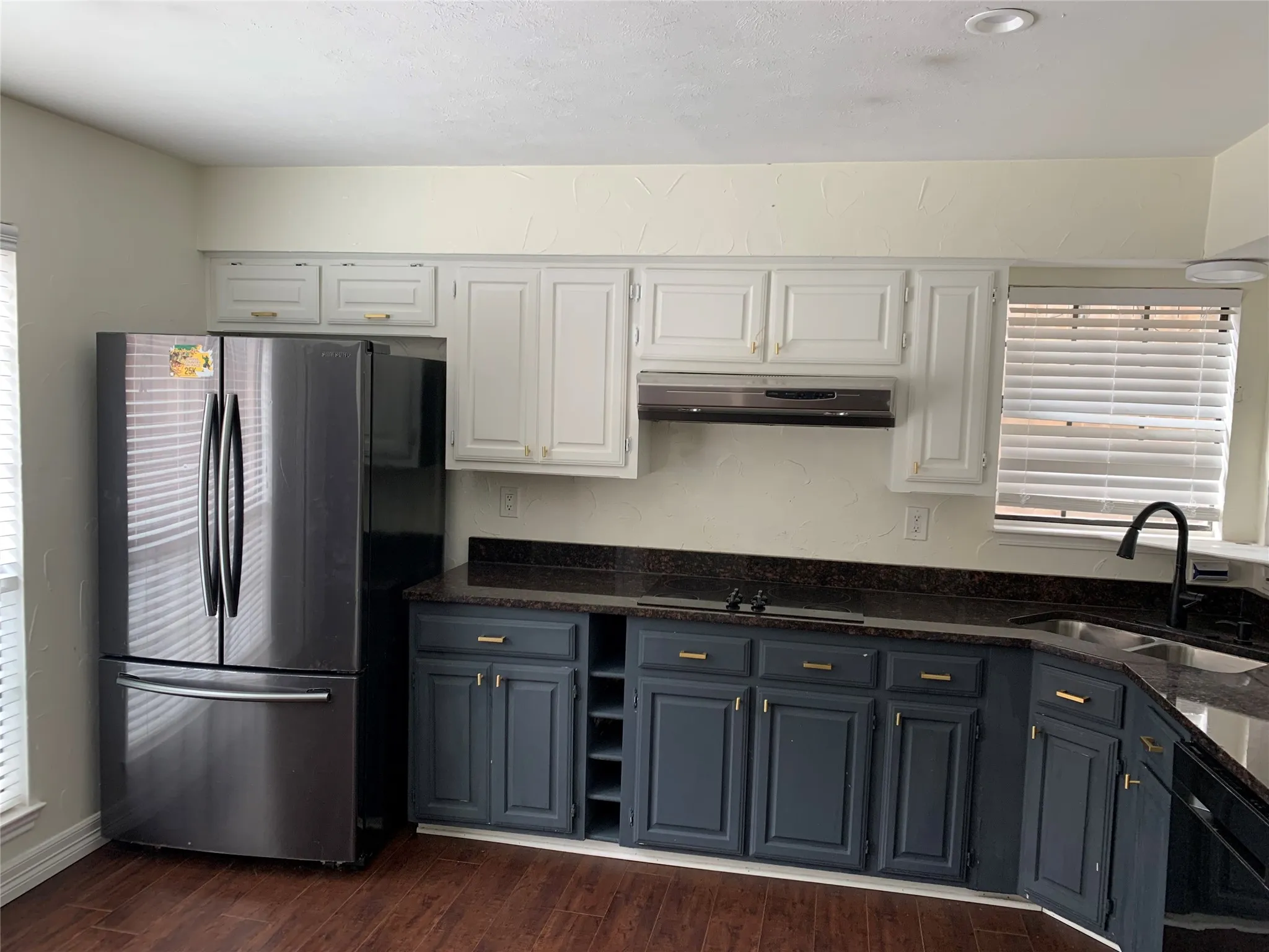 Kitchen with sink, dark wood-type flooring, white cabinetry, black appliances, and dark stone counters