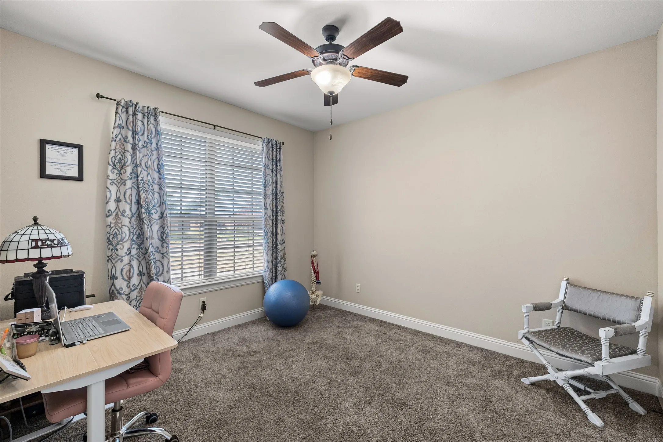 Carpeted room featuring a window with horizontal blinds, a ceiling fan with integrated lighting, and neutral wall tones