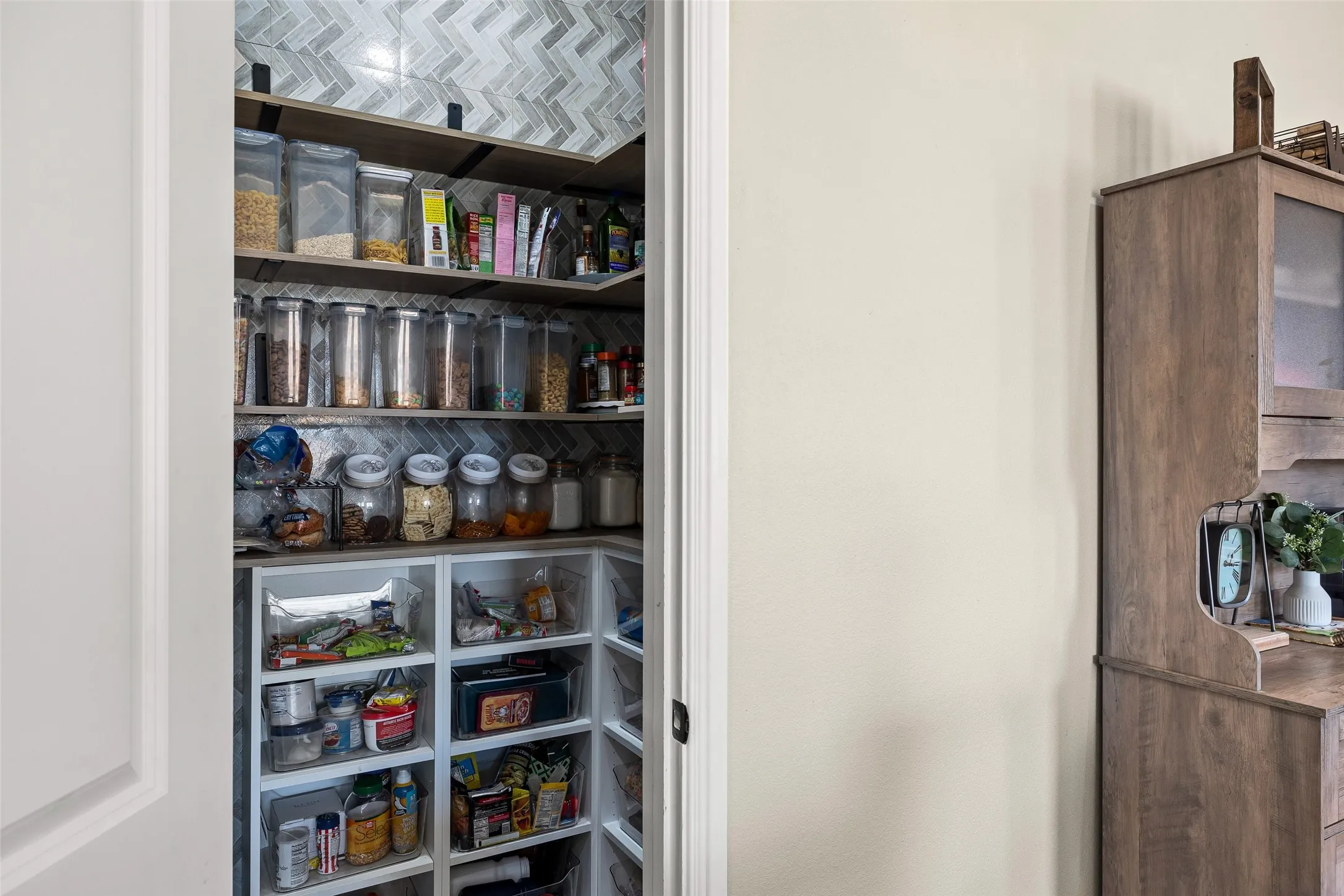 Pantry featuring chevron tile backsplash, built-in shelving, and wood-finish shelving