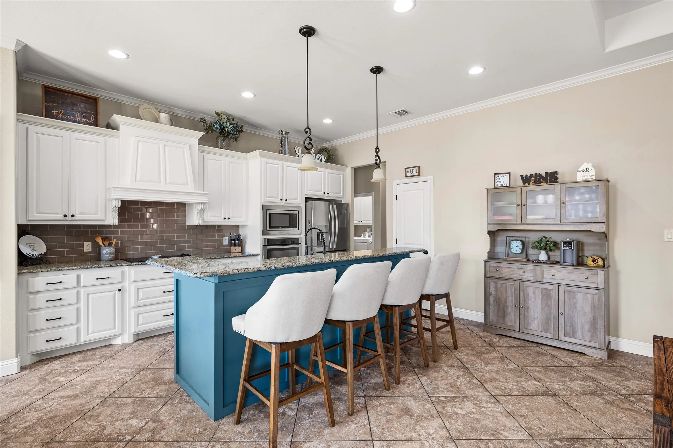Kitchen featuring a large central island, white cabinetry, integrated stainless steel appliances, a tiled backsplash, and recessed lighting