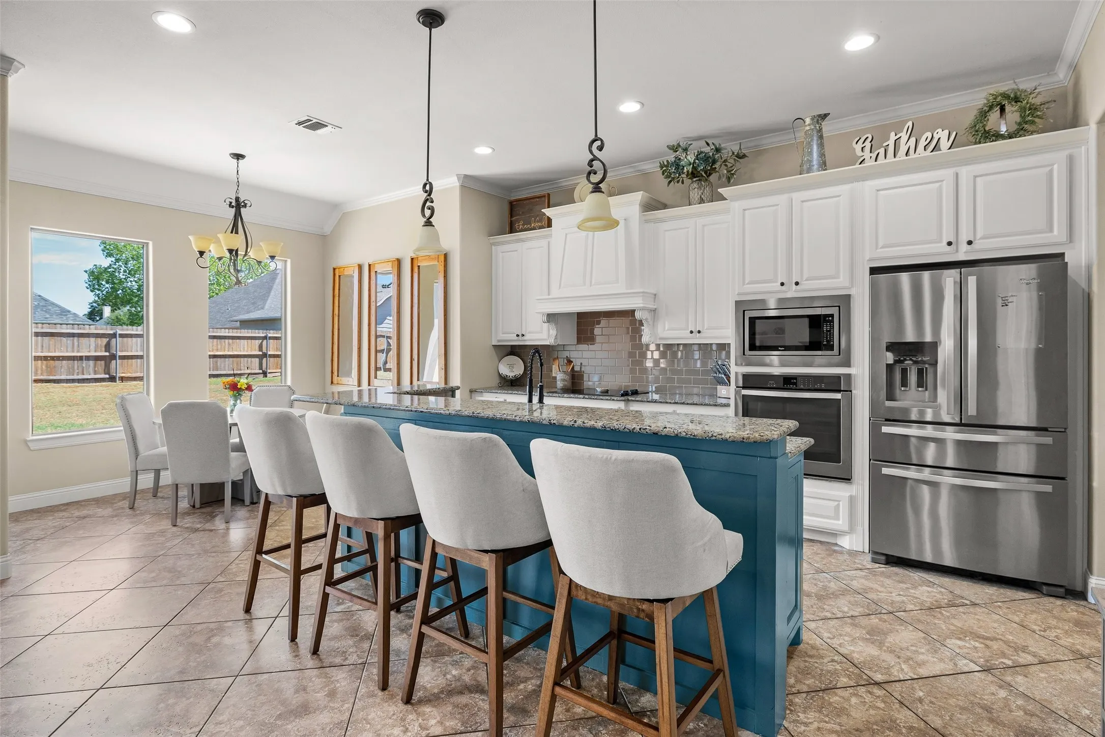 Kitchen featuring a two-tier island with a contrasting base, white shaker-style cabinetry, stainless steel appliances, a tile backsplash, and recessed lighting