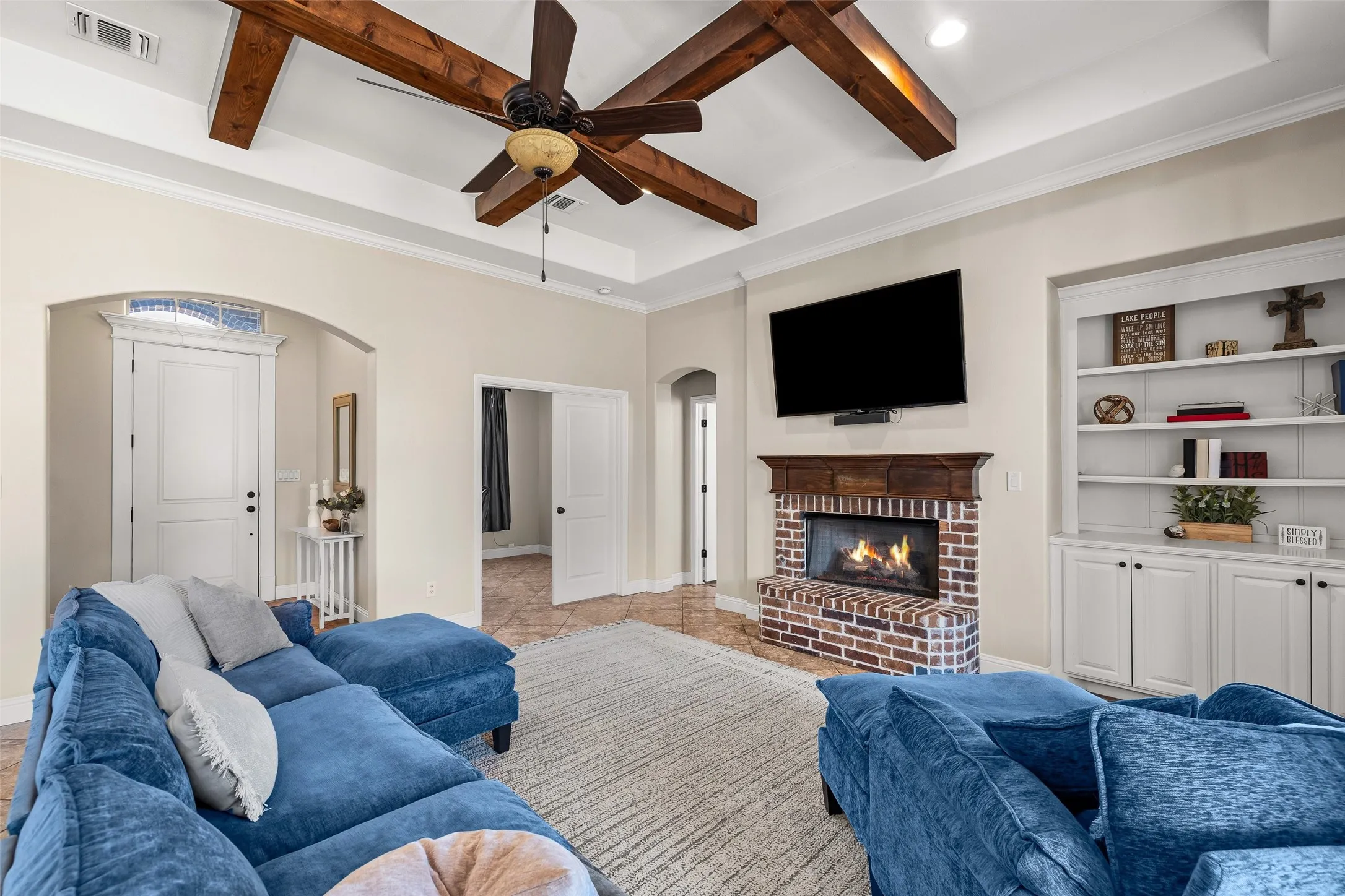 Tray ceiling with exposed wood beams and a ceiling fan