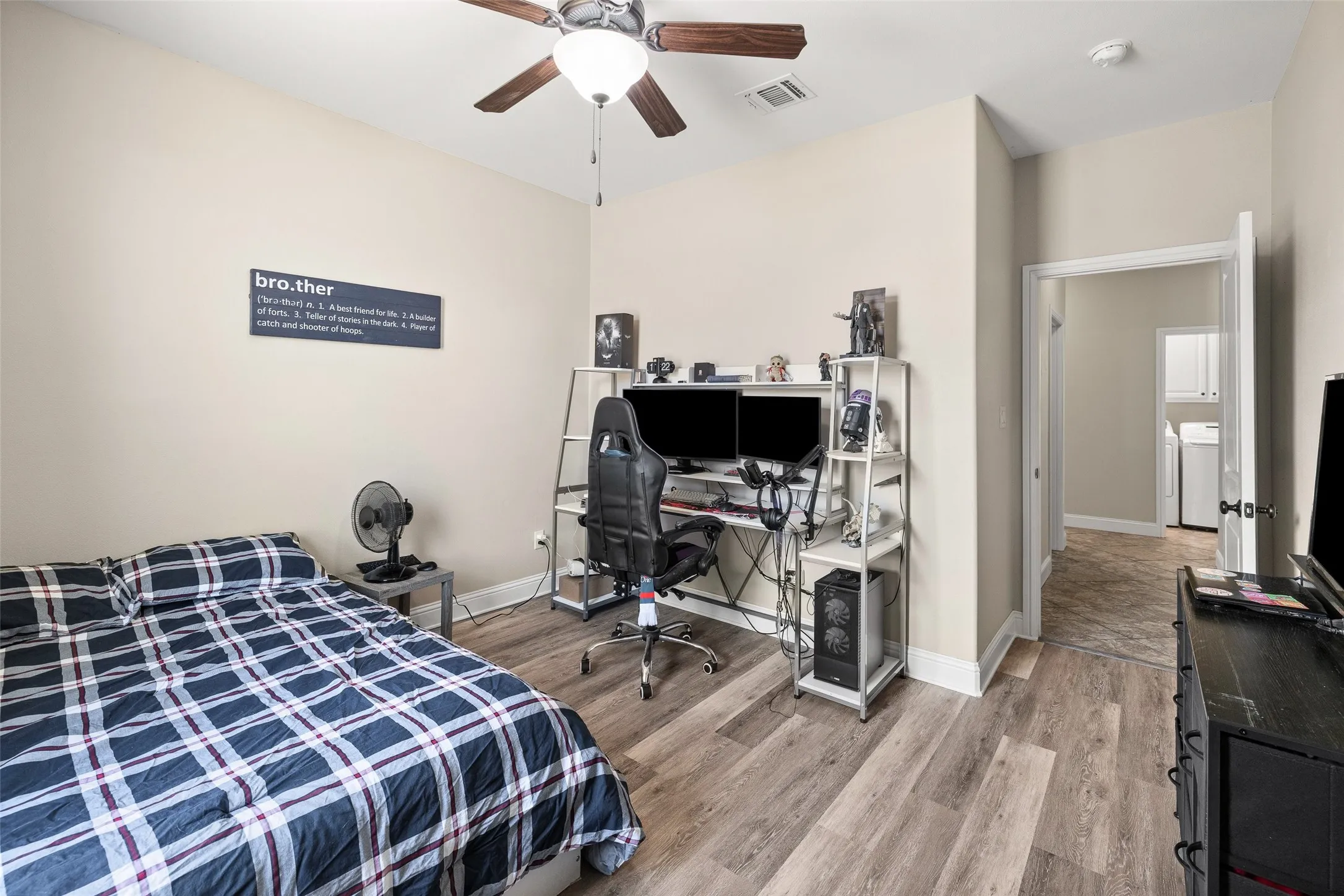 Light wood-finish flooring, ceiling fan with light fixture, neutral wall color, and an open doorway