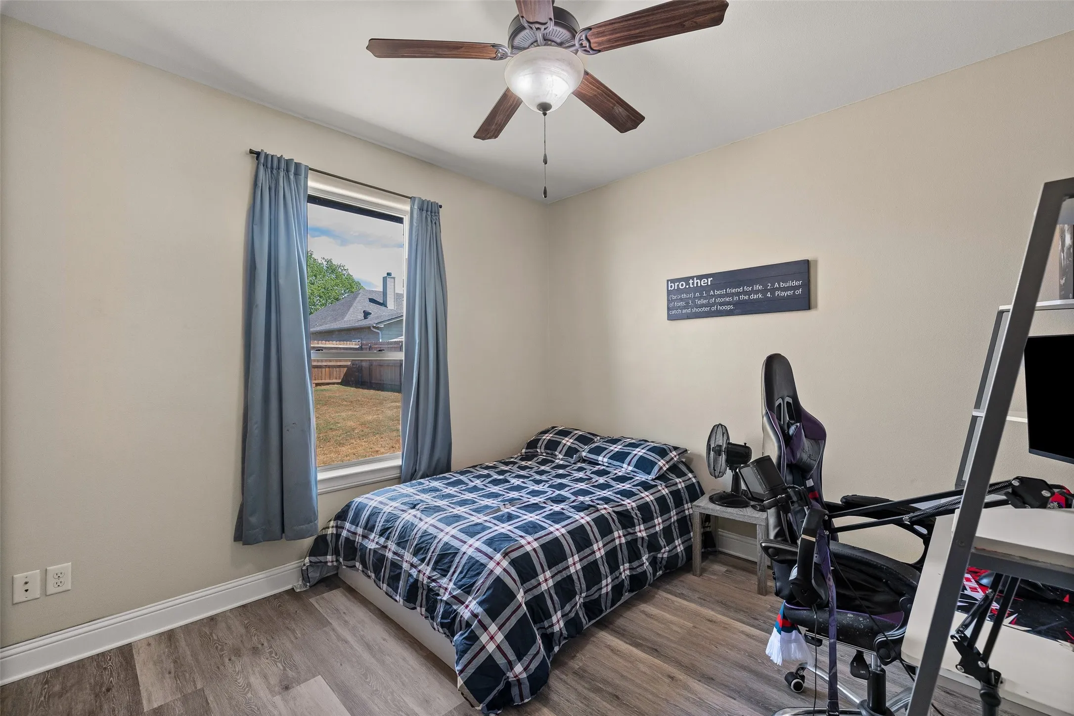 Wood-finish flooring, single window with curtains, and a ceiling fan with light fixture
