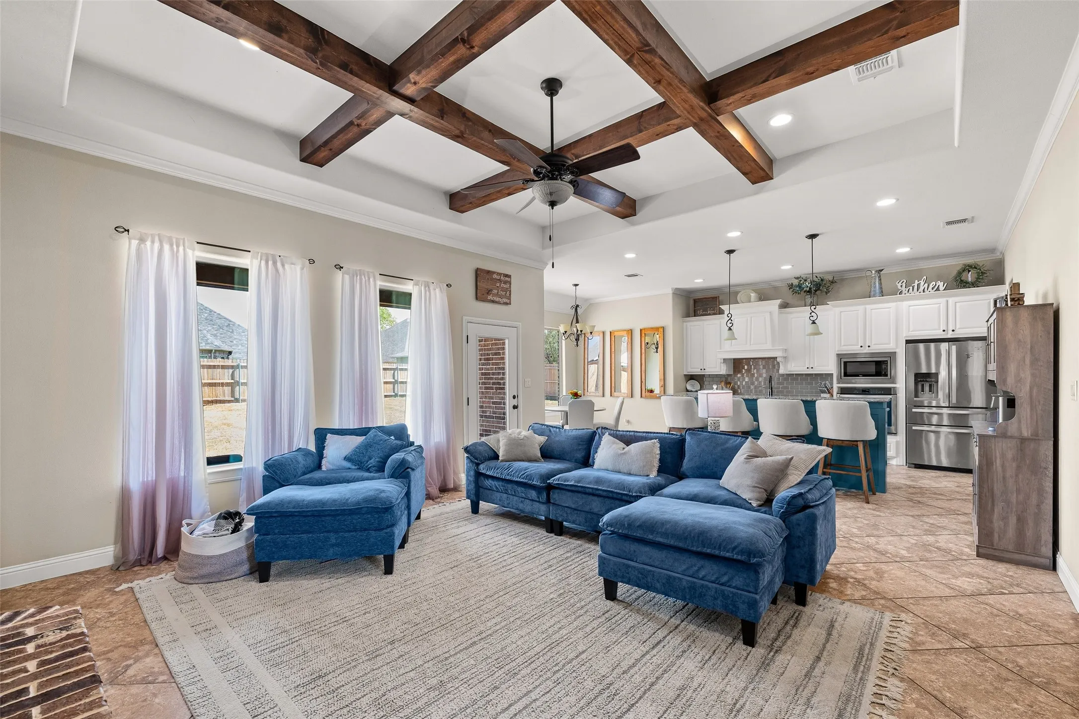 Tray ceiling with exposed wood beams, recessed lighting, ceiling fan, multiple windows, and tile flooring