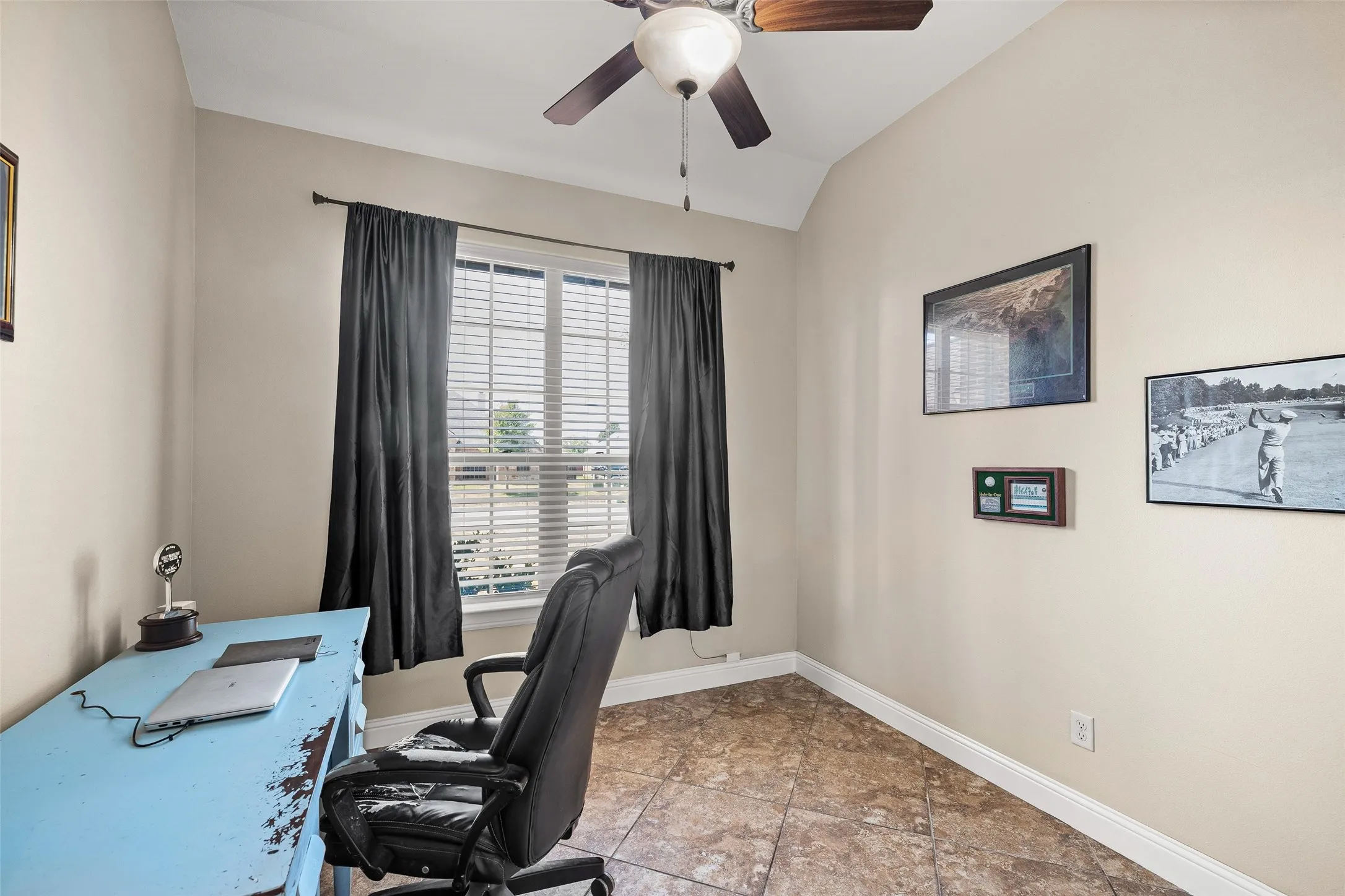 Vaulted ceiling, ceiling fan, window with horizontal blinds, tile flooring, and neutral wall paint