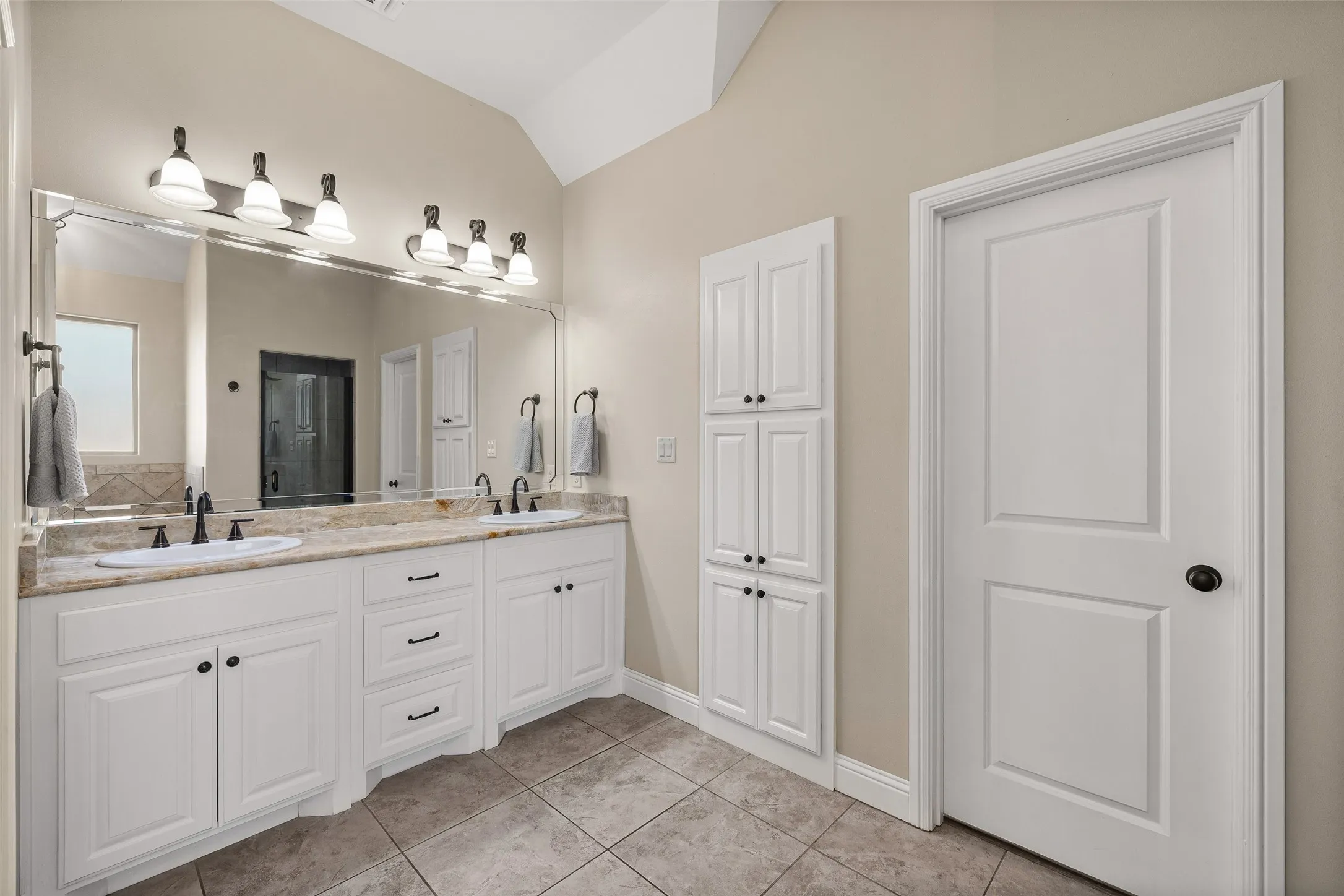 Dual vanity with white cabinetry, integrated sinks, and stone countertop