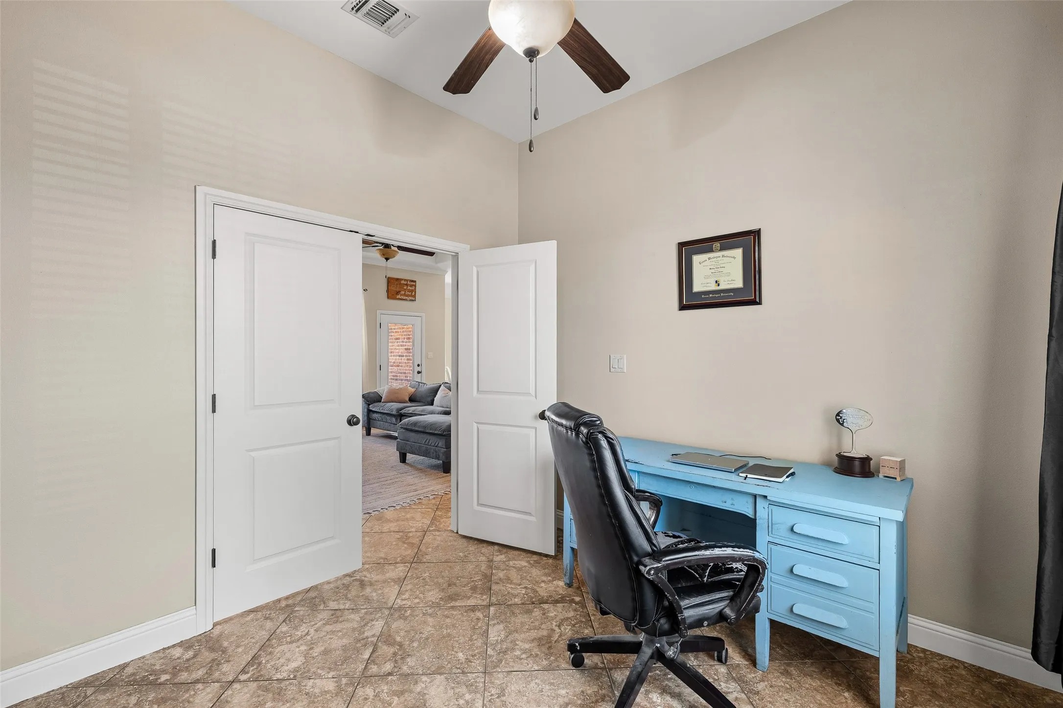Vaulted ceiling with a ceiling fan, light-colored walls, tile flooring, and white double doors