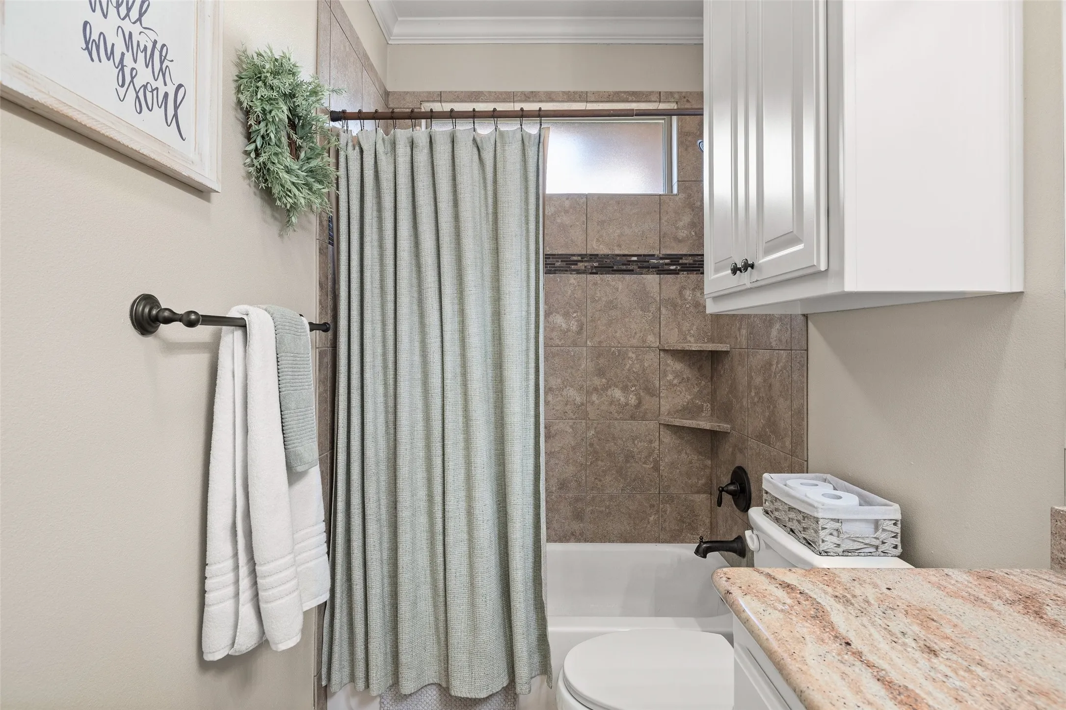 Bathtub with tile surround, built-in shelving, and a privacy window