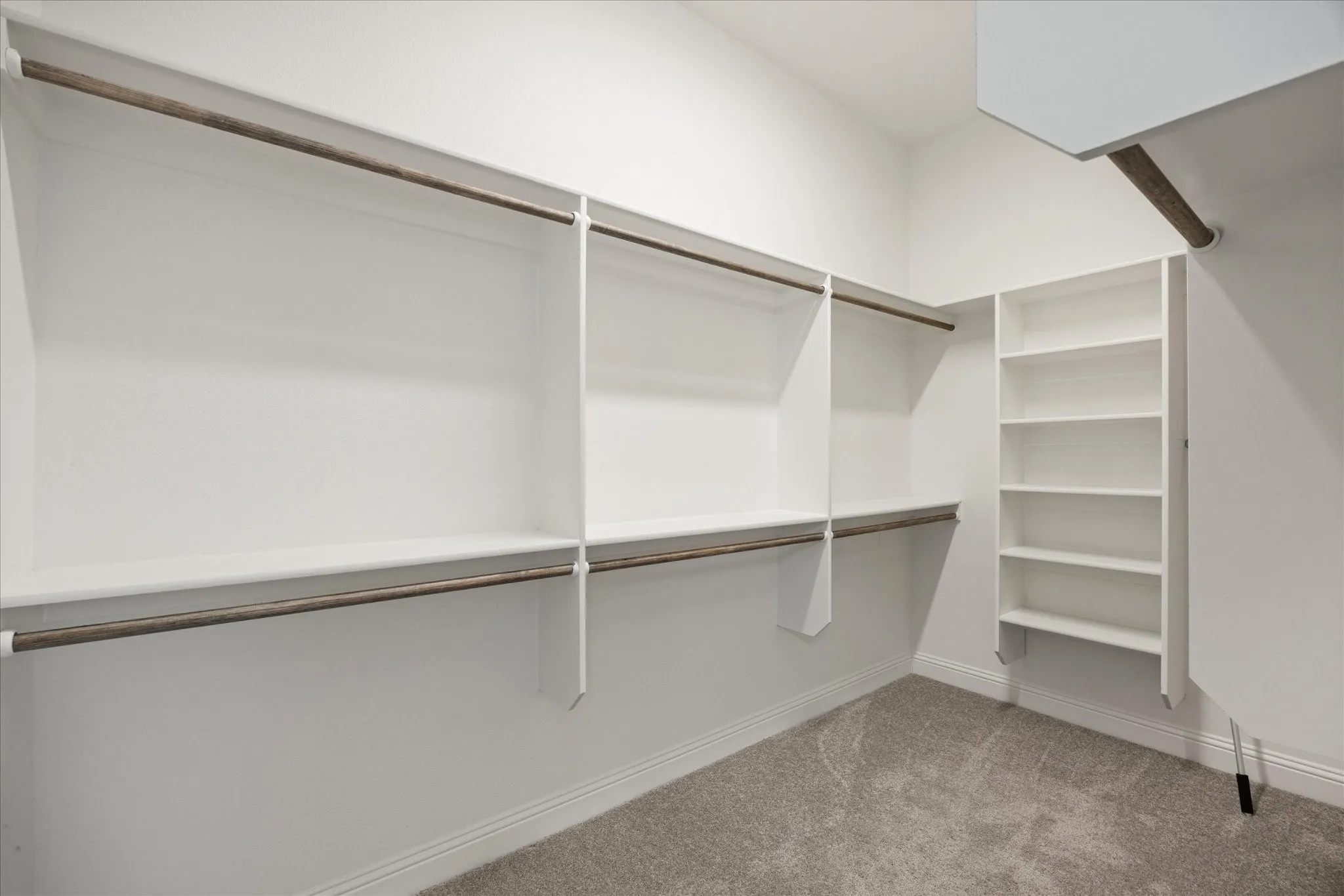 Custom closet system featuring built-in shelving, multiple hanging rods, and an integrated white storage unit with several shelves