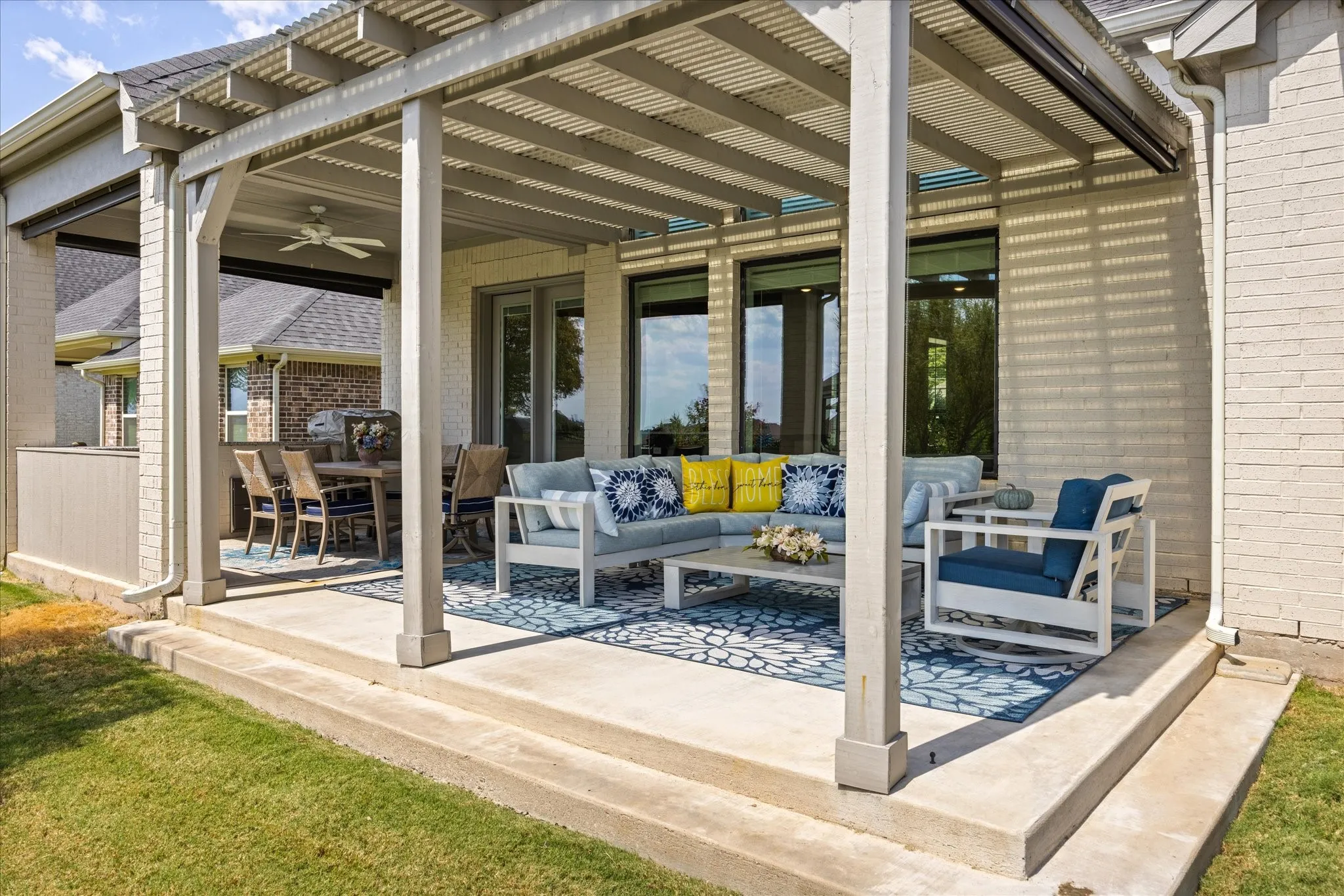 Expansive concrete patio featuring a louvered pergola, integrated ceiling fan, and large framed windows