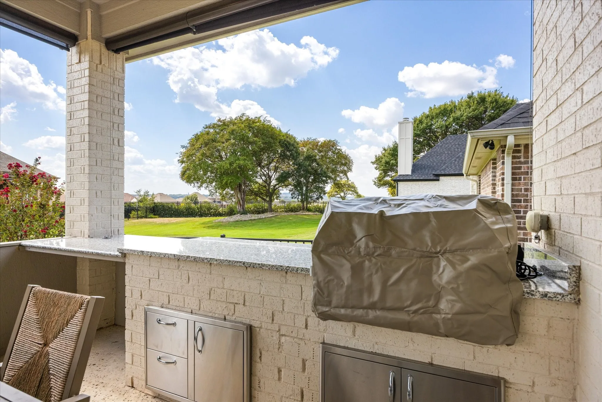 Covered patio featuring a built-in outdoor kitchen with stainless steel appliances and stone countertops
