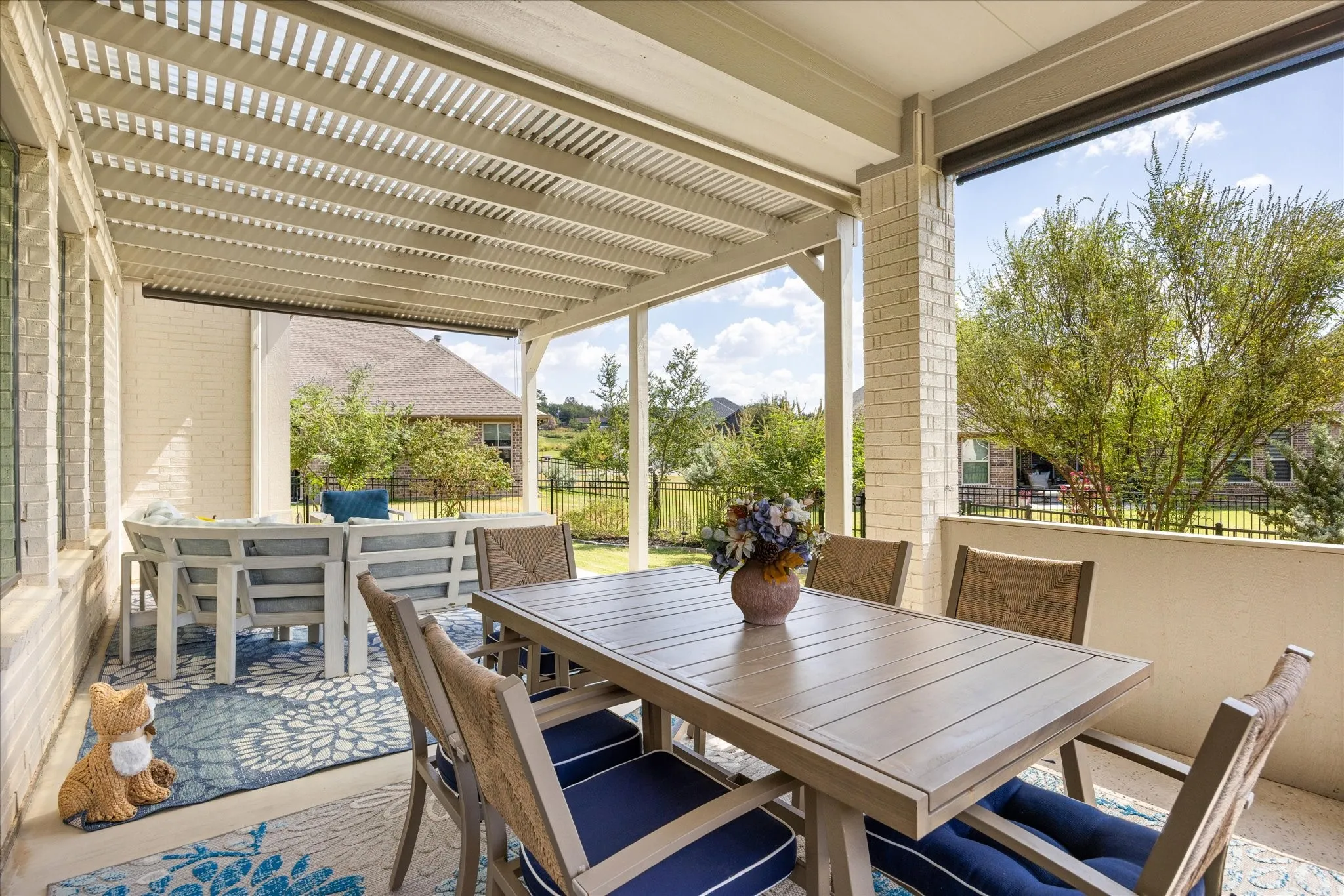 Covered outdoor patio featuring a slatted pergola roof and brick columns