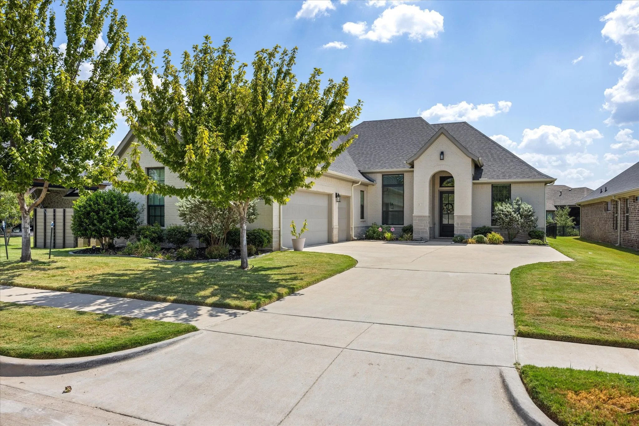 Stucco exterior with stone accents, a dark-toned gabled roof, an arched entryway, and an attached two-car garage