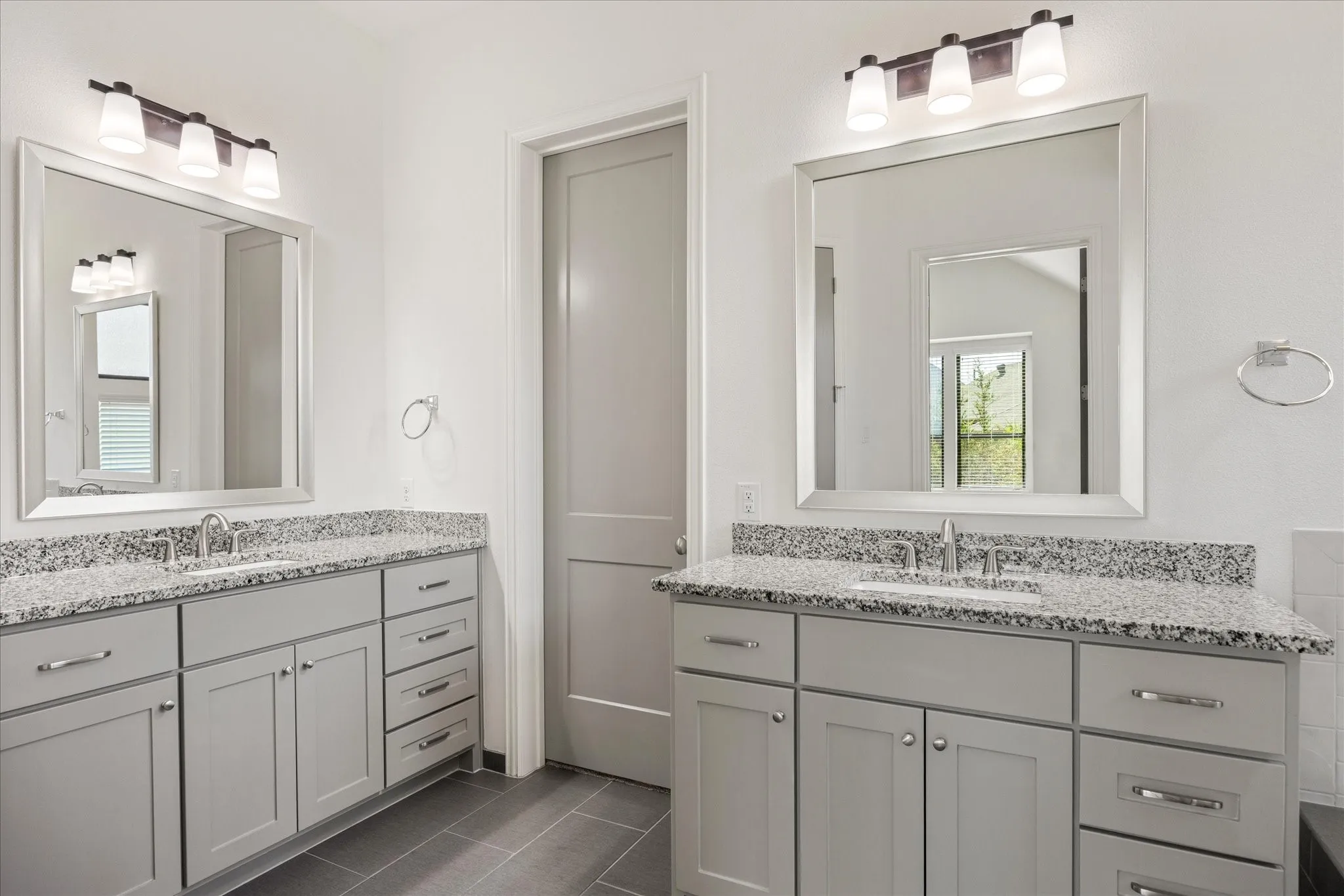 Dual vanity featuring gray shaker cabinetry, speckled countertop, and rectangular mirrors