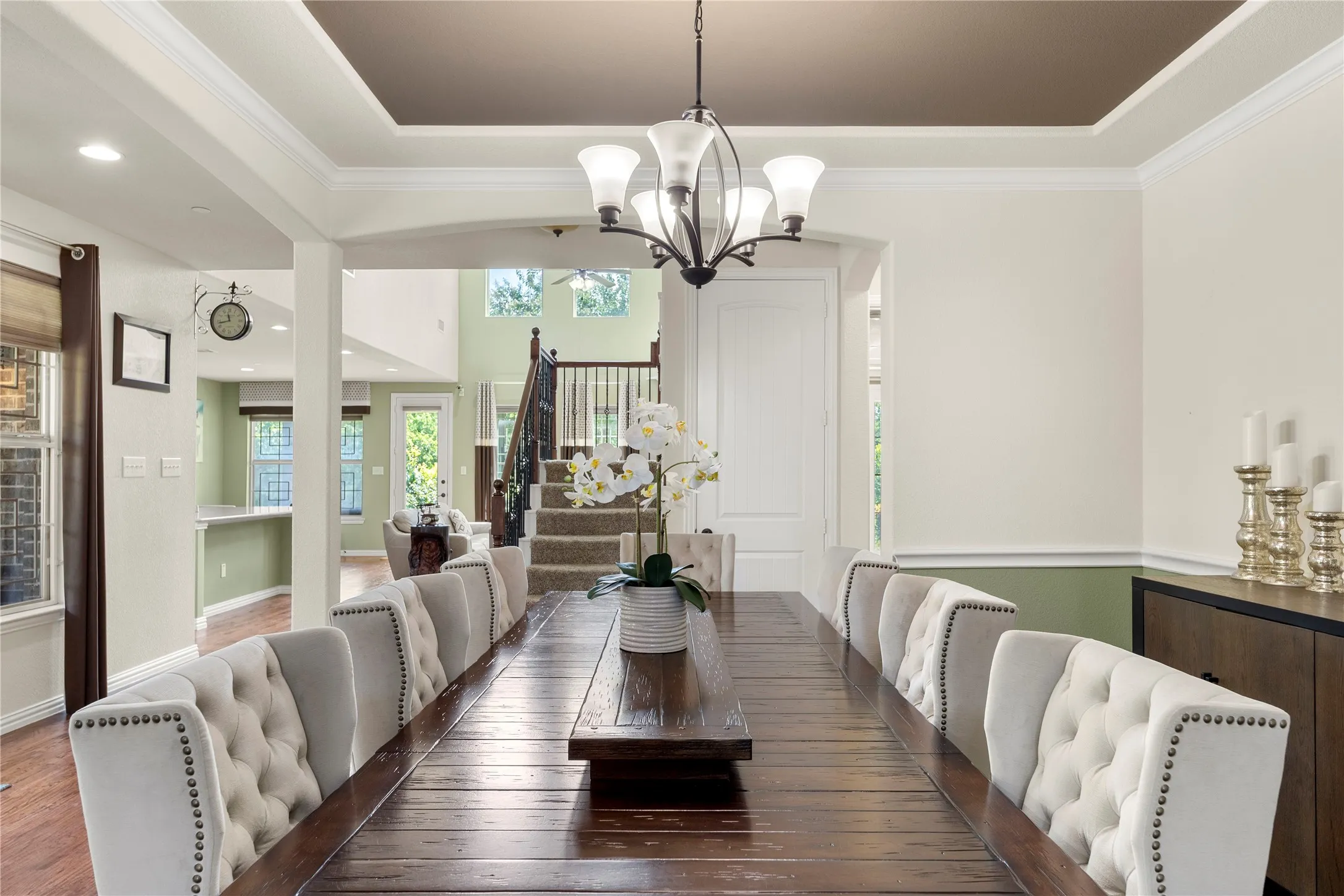 Formal dining area featuring a tray ceiling with crown molding, a dark wood-finish dining table, and a contemporary chandelier