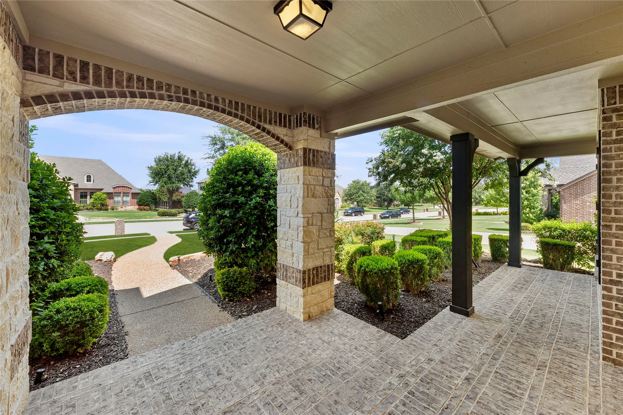 Covered entryway featuring brick flooring, stone and brick columns, and a decorative ceiling light fixture