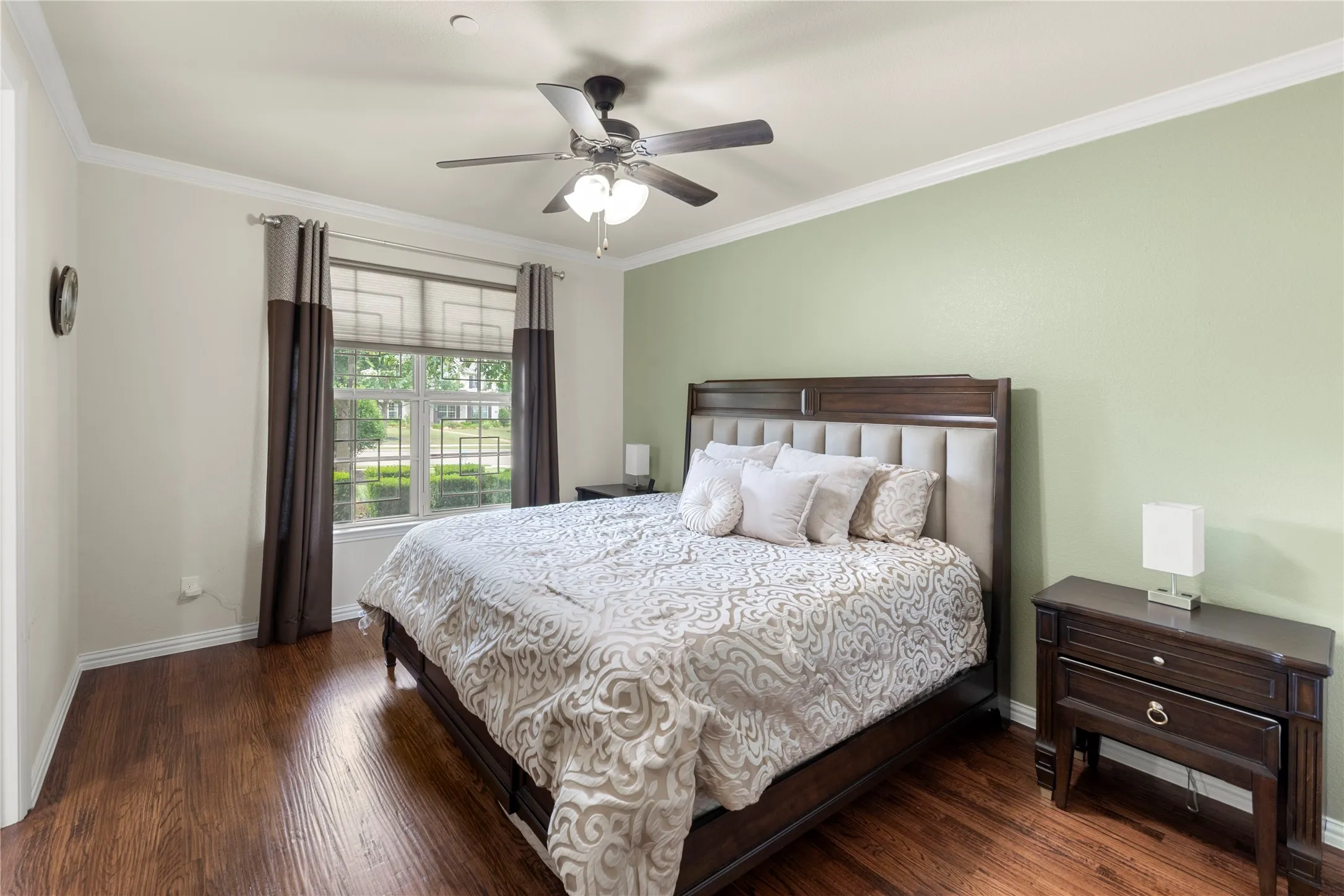 Spacious room featuring wood-finish flooring, a ceiling fan, and crown molding