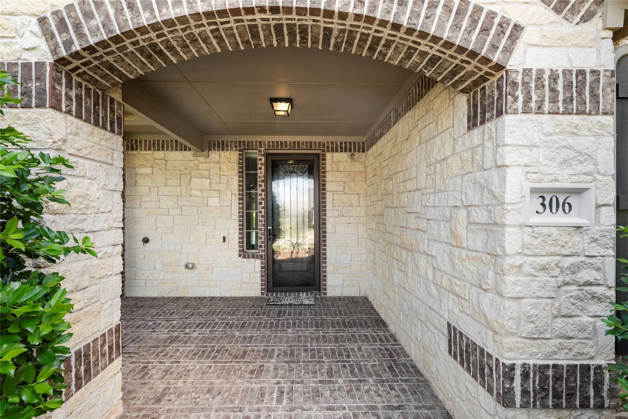 Covered entryway featuring light-colored stone and brick detailing