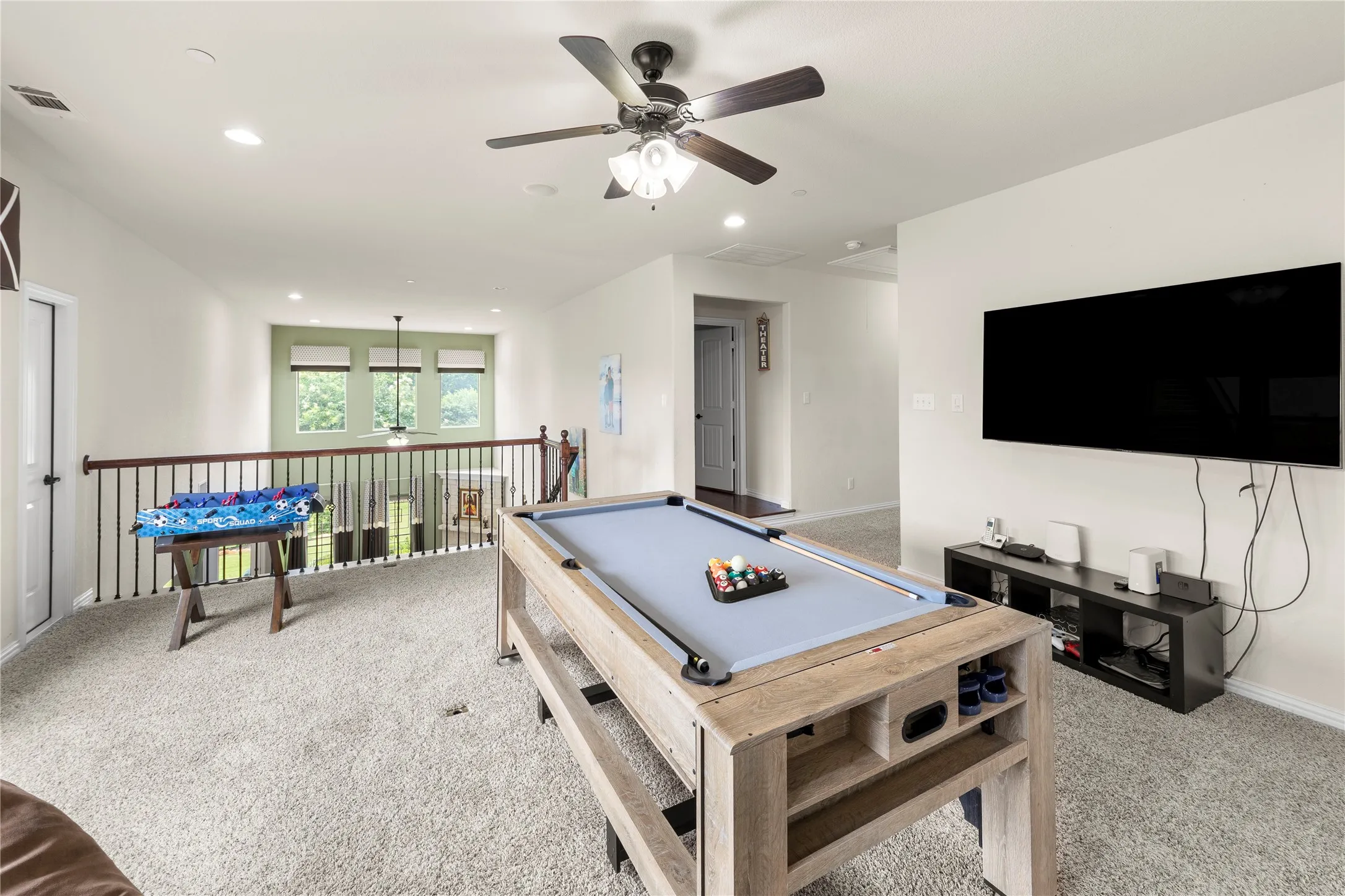 Spacious loft area featuring light-toned carpet flooring, recessed lighting, and a ceiling fan