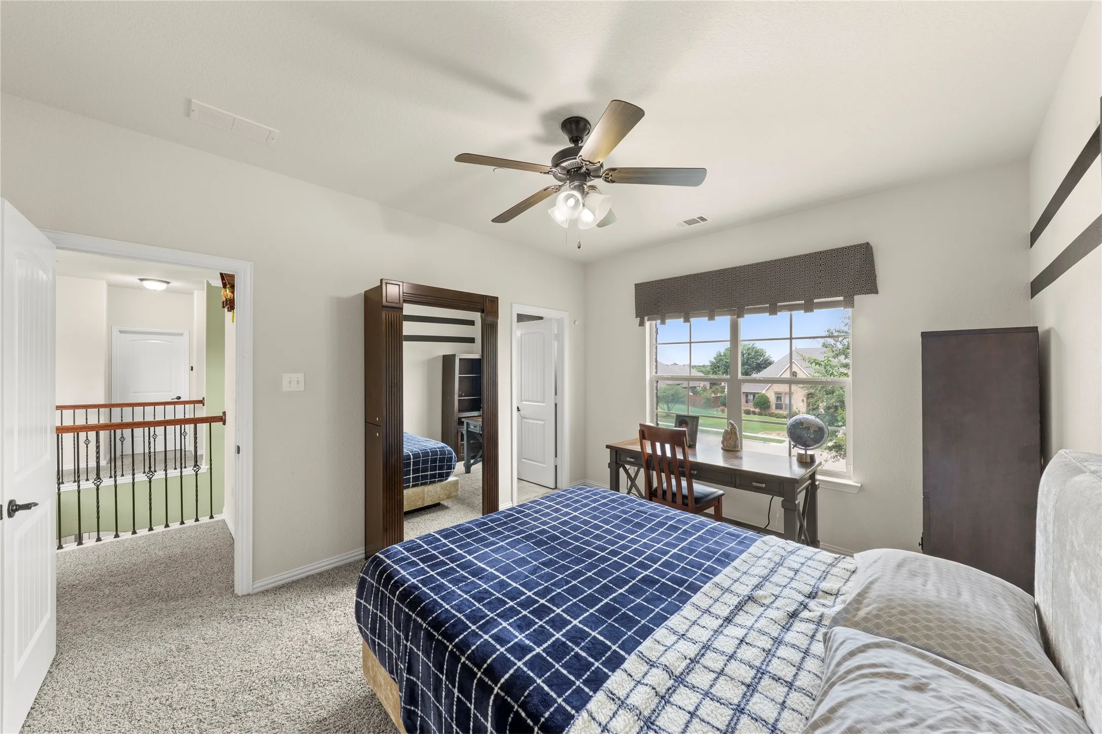 Carpeted room featuring a ceiling fan with integrated lighting, a large window with a valance, and a built-in closet with a mirrored door
