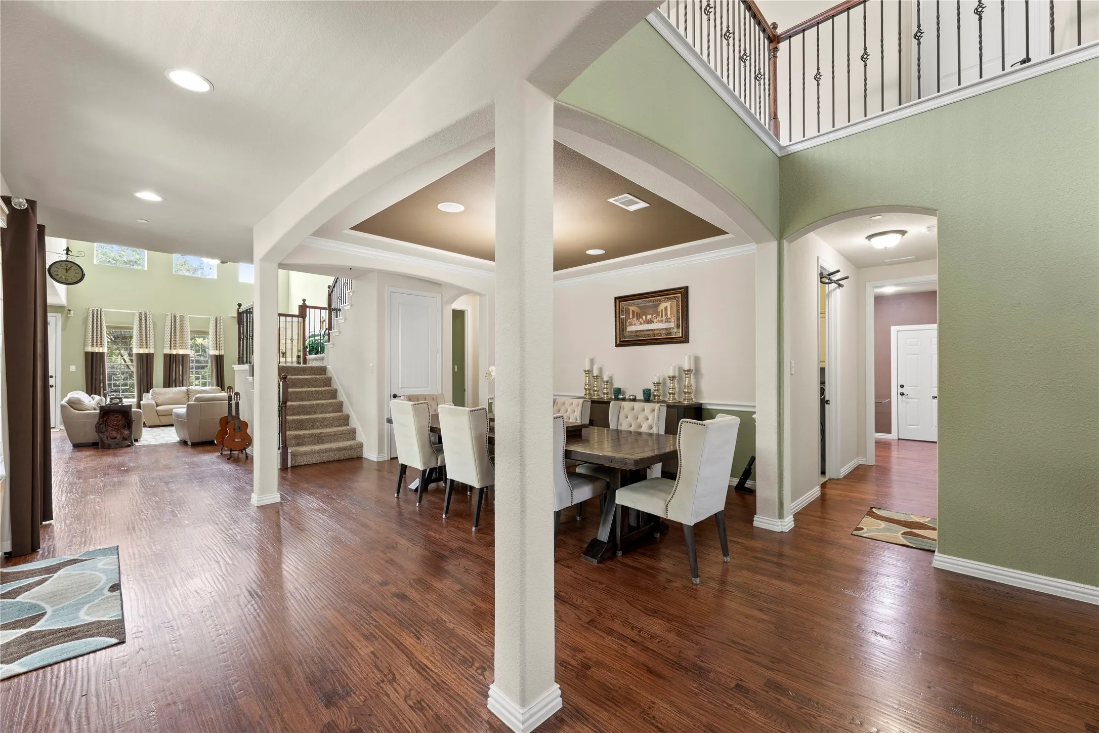 Open concept interior featuring wood-finish flooring, a formal dining area with recessed lighting, and an arched entry to a hallway