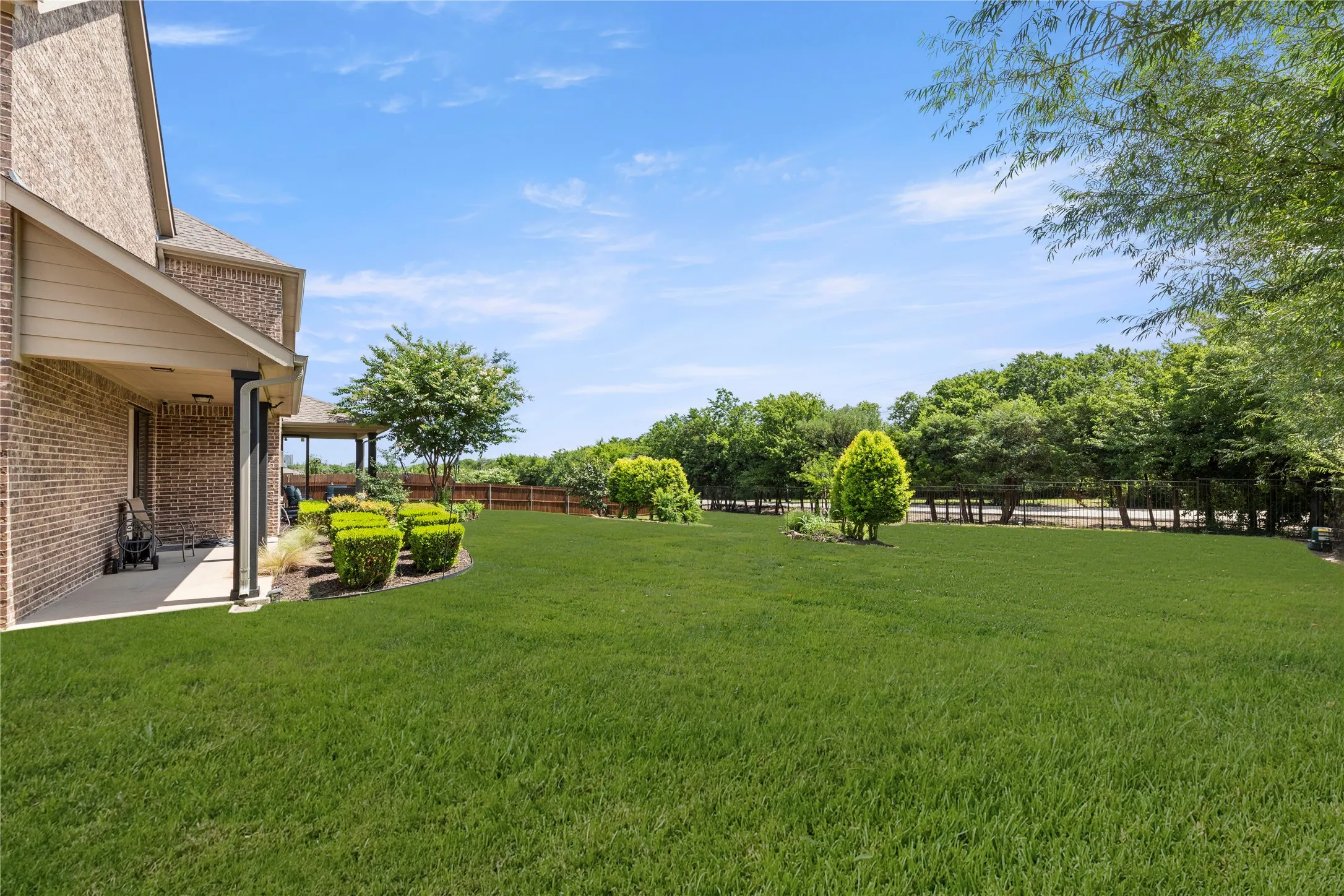 Expansive green lawn extending from a covered patio with brick exterior