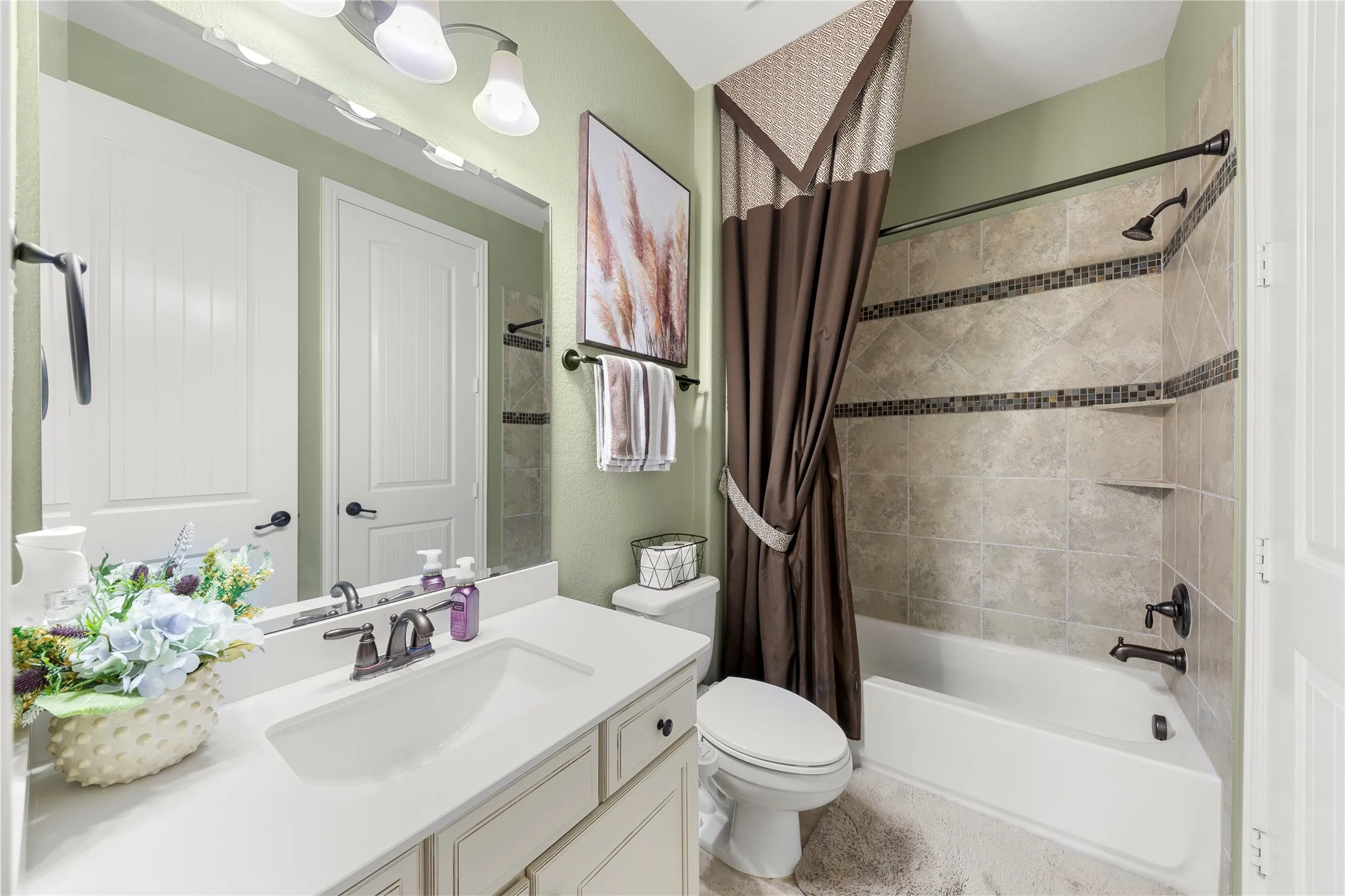 Bathroom featuring a single vanity with an integrated sink and bronze-tone faucet, a full-width mirror, and a wall-mounted light fixture
