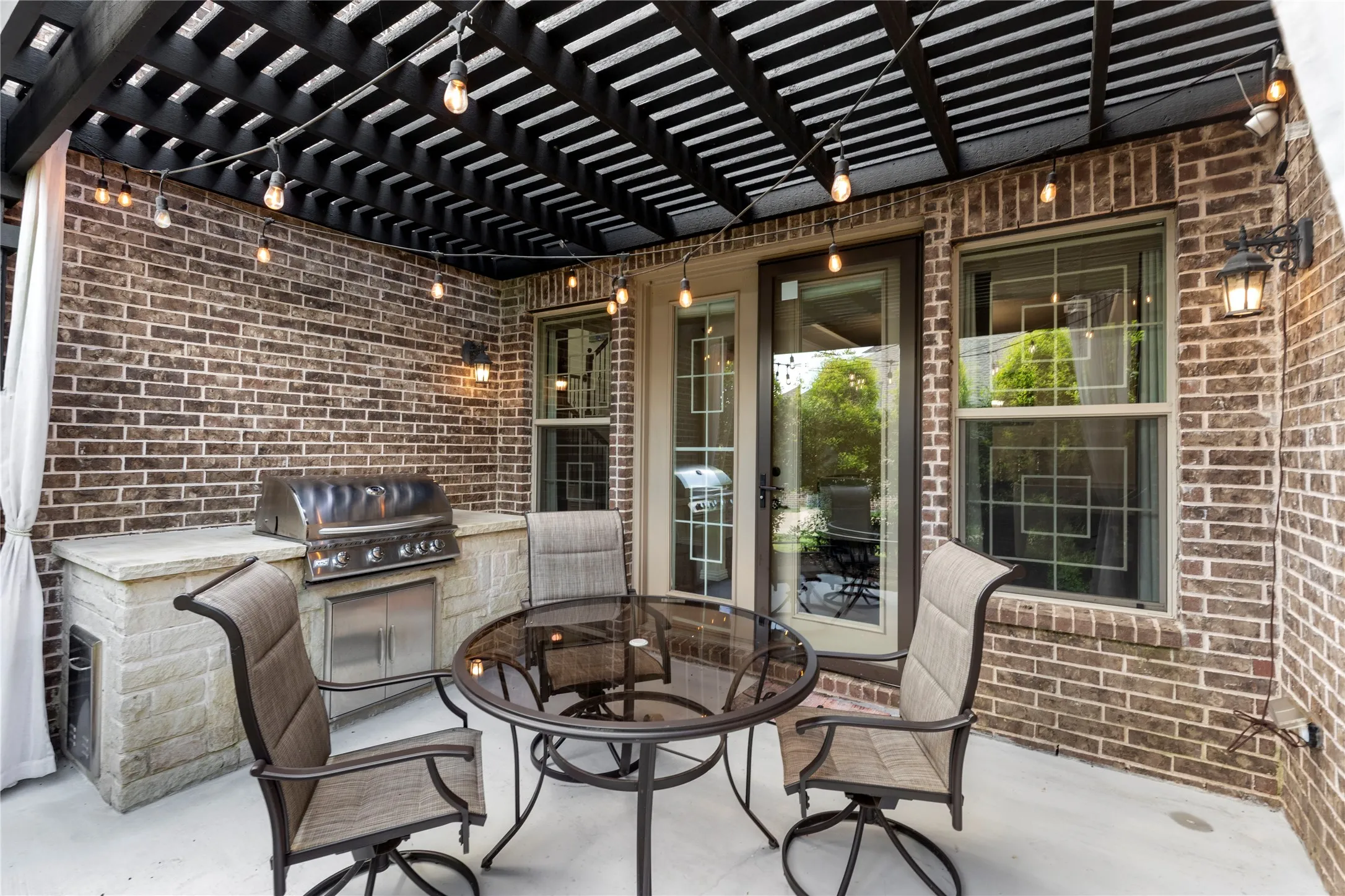 Covered side patio featuring a built-in outdoor kitchen with stainless steel grill, granite countertop, and solid surface countertop