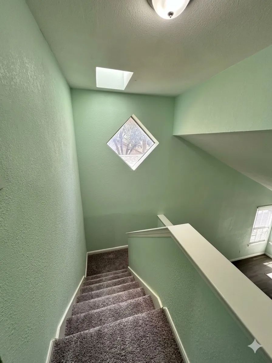 Carpeted staircase with a window, skylight, and ceiling-mounted light fixture