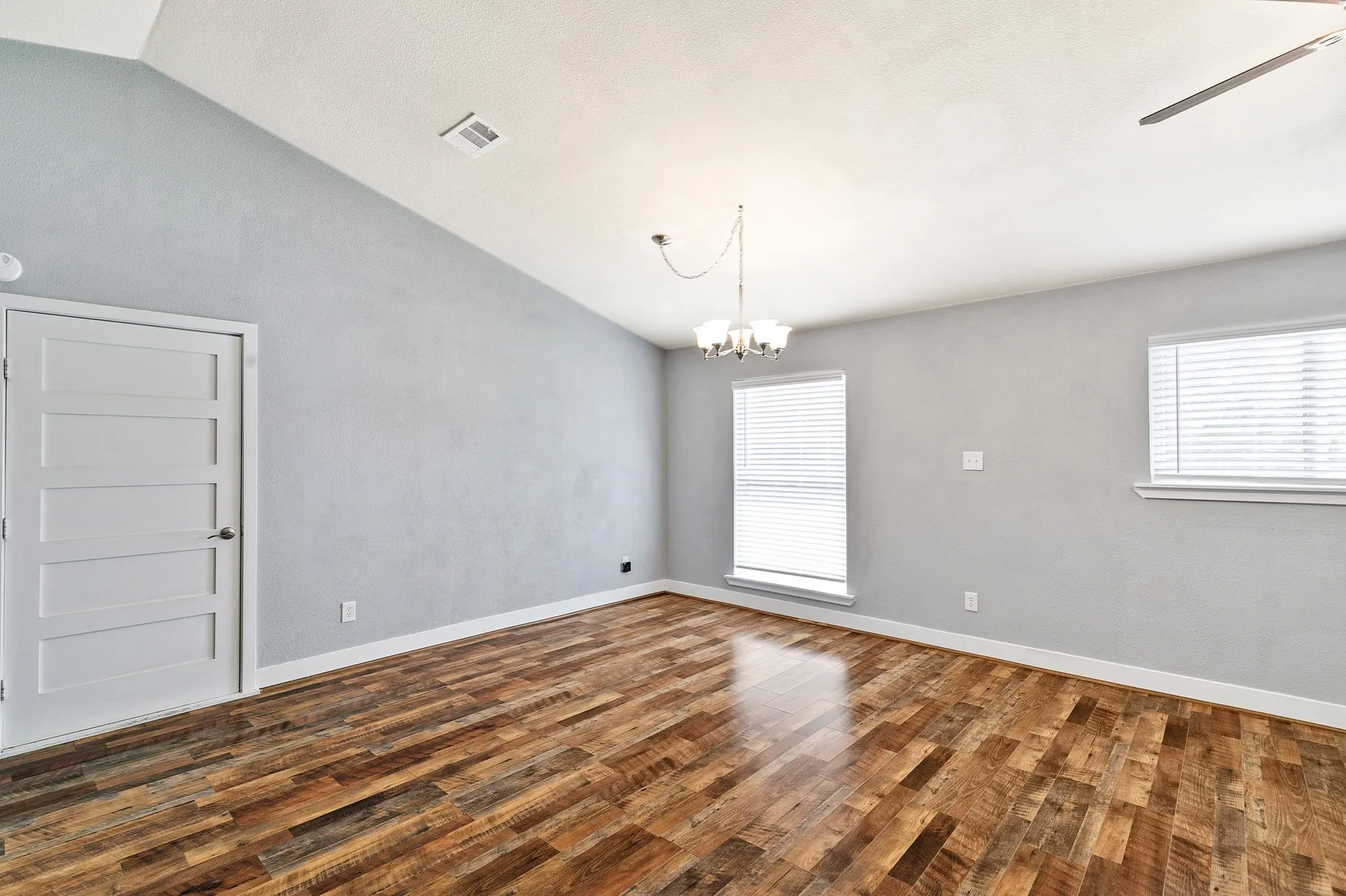 Vaulted ceiling with a contemporary chandelier and ceiling fan
