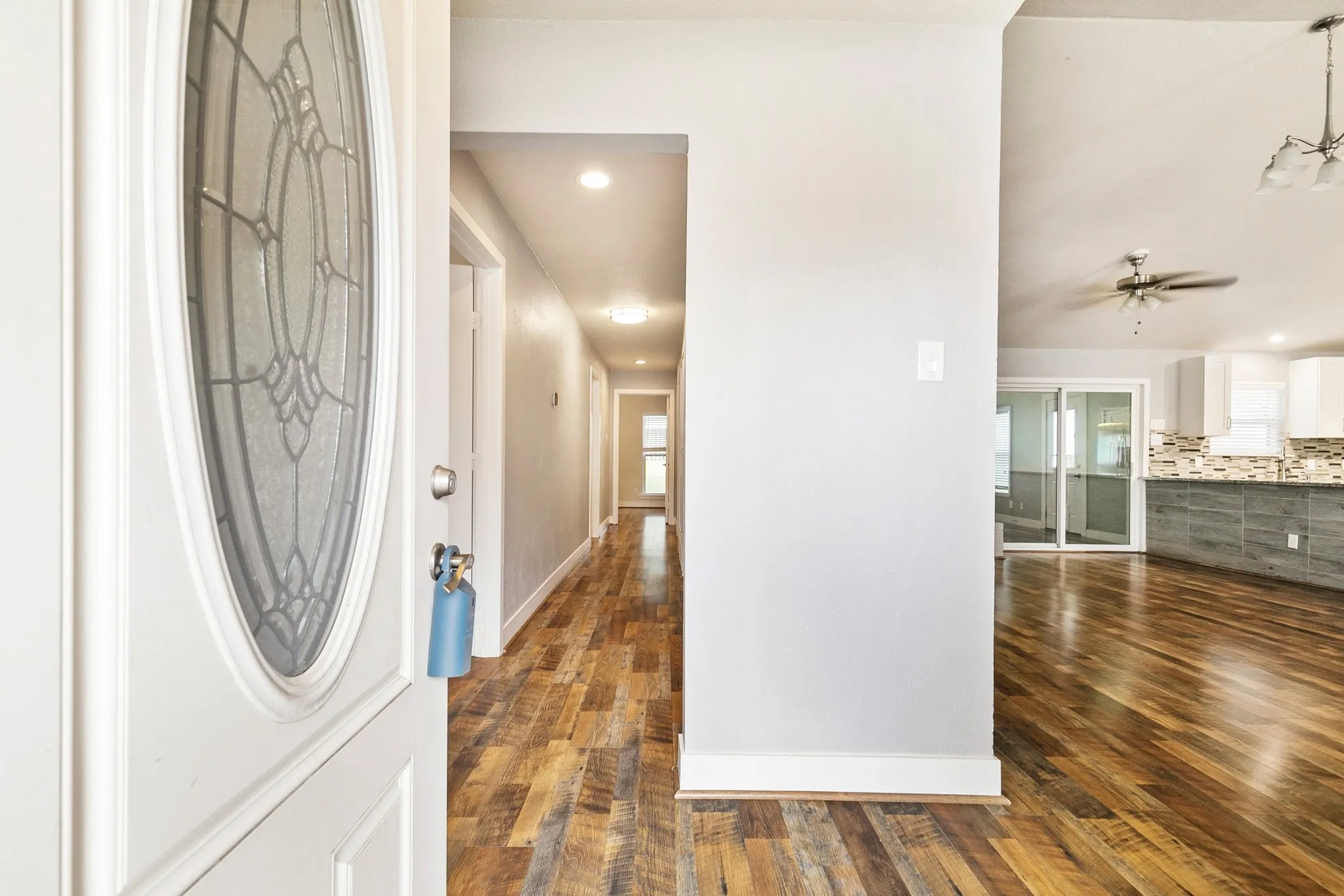 Entry with leaded glass door, wood-finish flooring, recessed lighting, and an open concept living area with vaulted ceilings