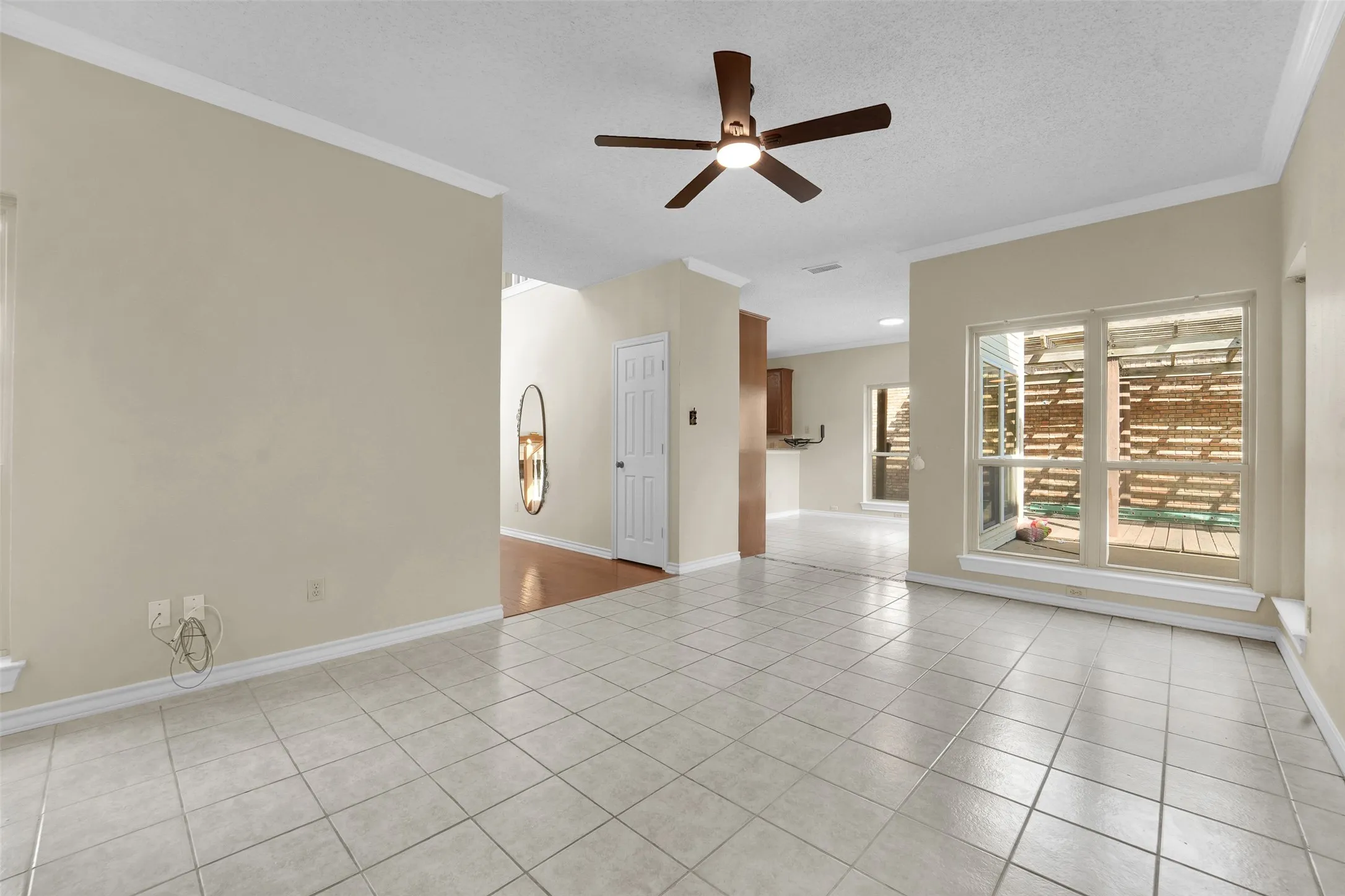 Neutral tone paint throughout, crown molding, tile flooring, and a ceiling fan