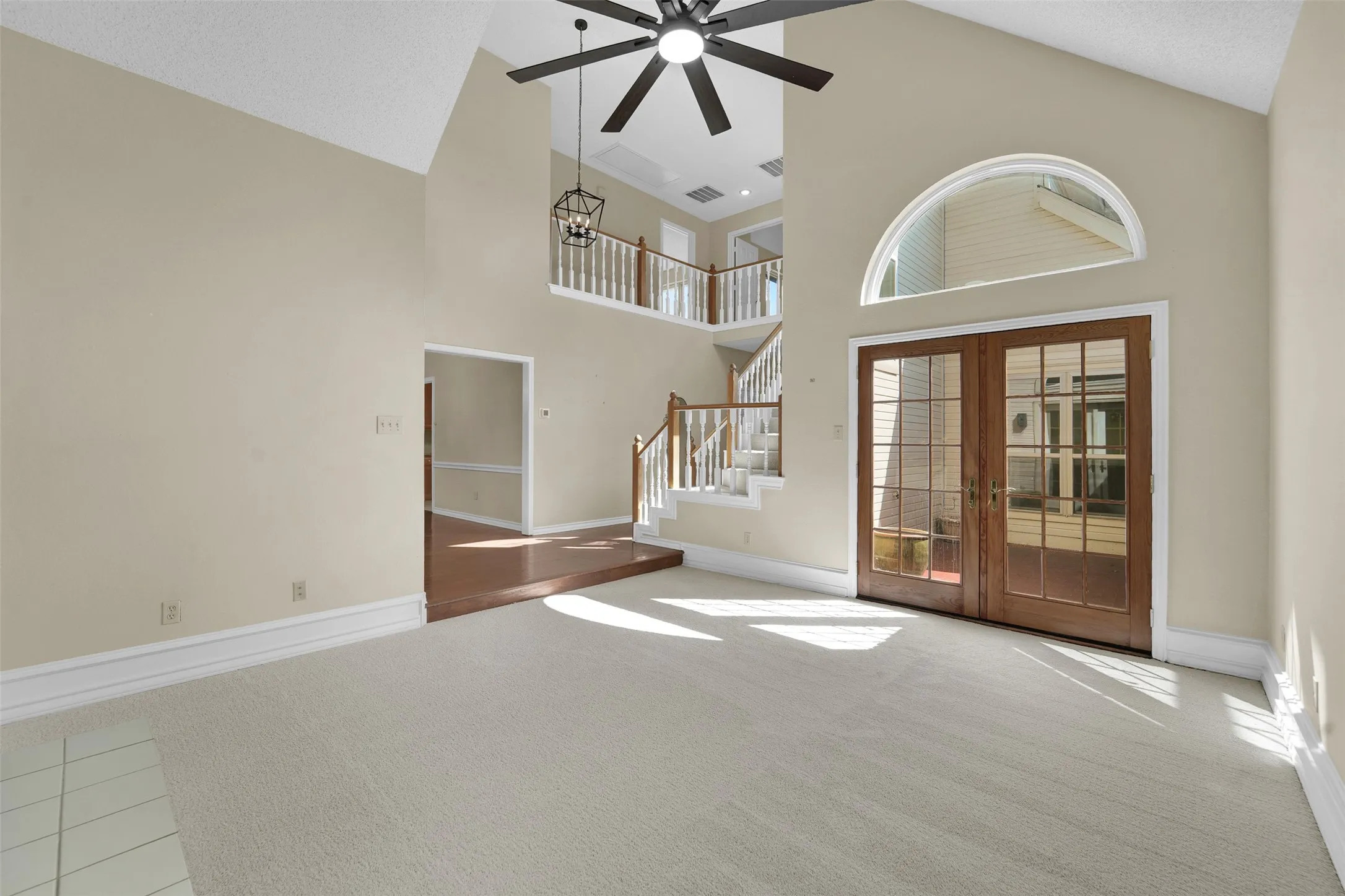 Vaulted ceilings, a dark wood-finish ceiling fan, and a light-colored carpeted floor