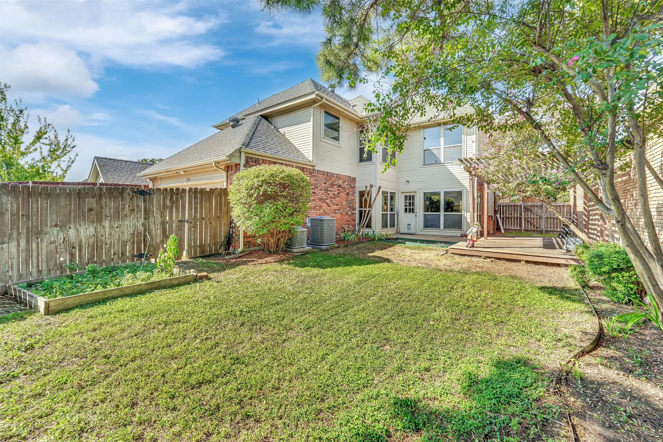 Expansive backyard featuring a manicured lawn, raised garden bed, and a wooden deck