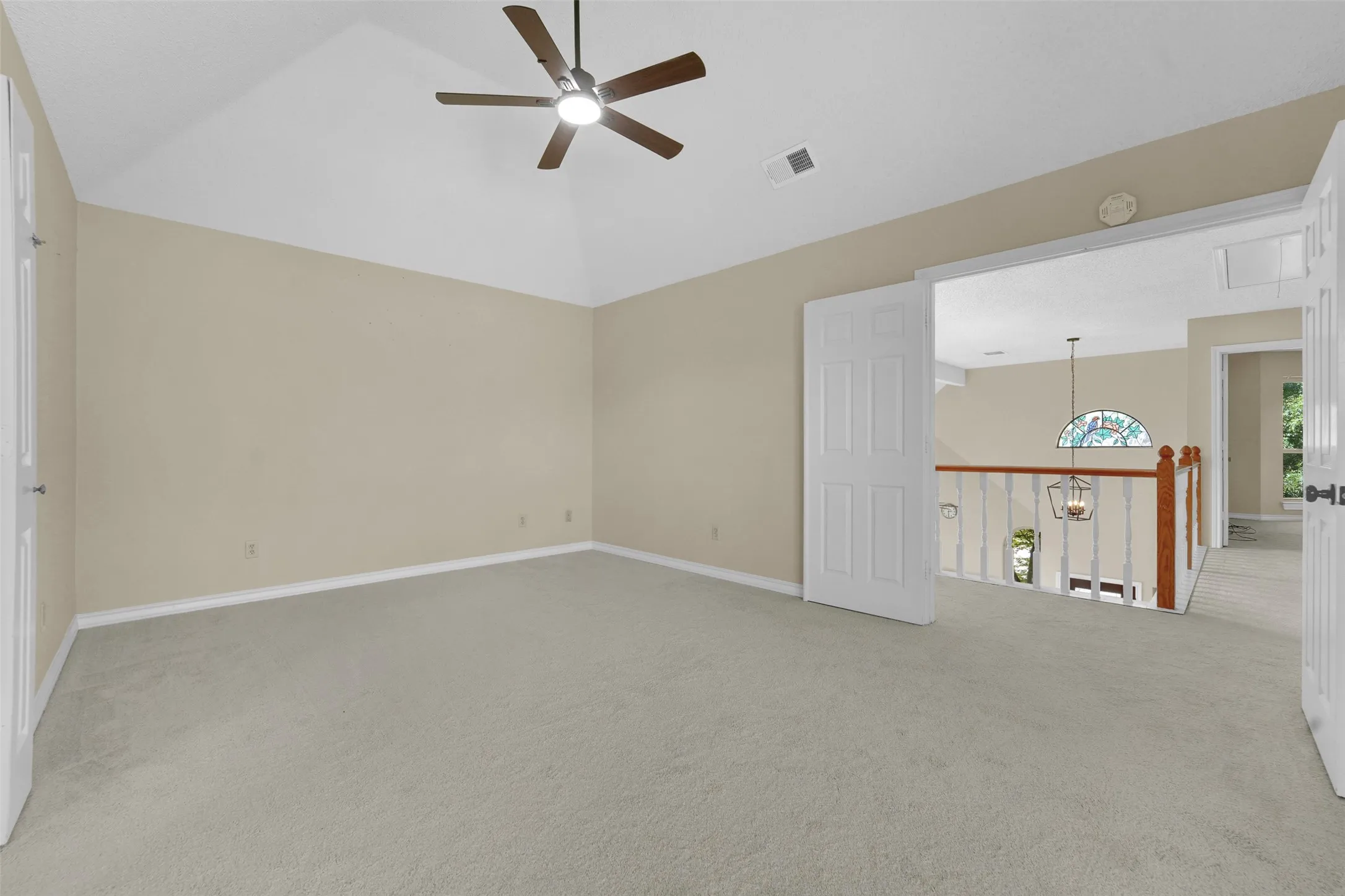 Vaulted ceiling with a ceiling fan, neutral wall color, and light-toned carpeting