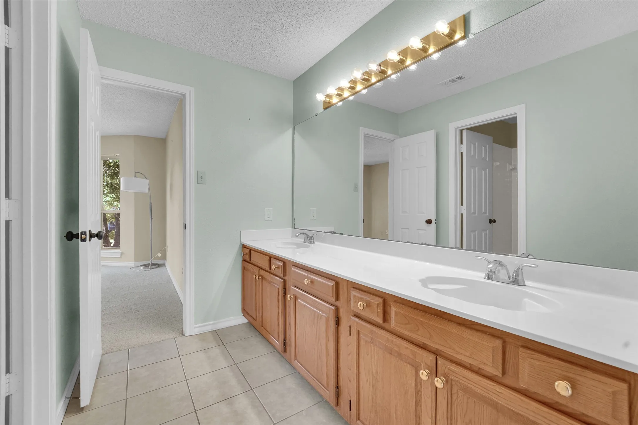 Dual basin vanity with wood-finish cabinetry and white countertop