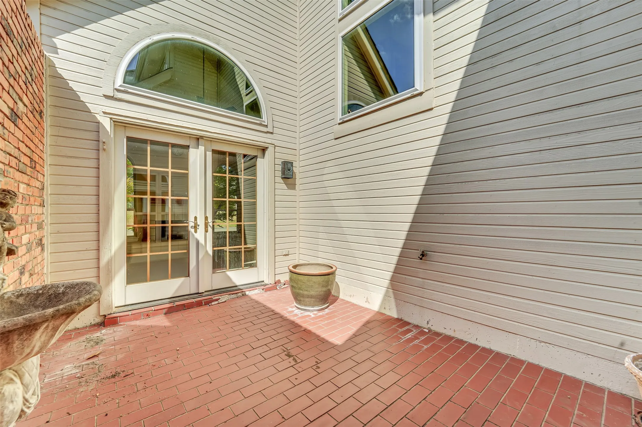 Brick patio with double French doors, transom window, and siding exterior